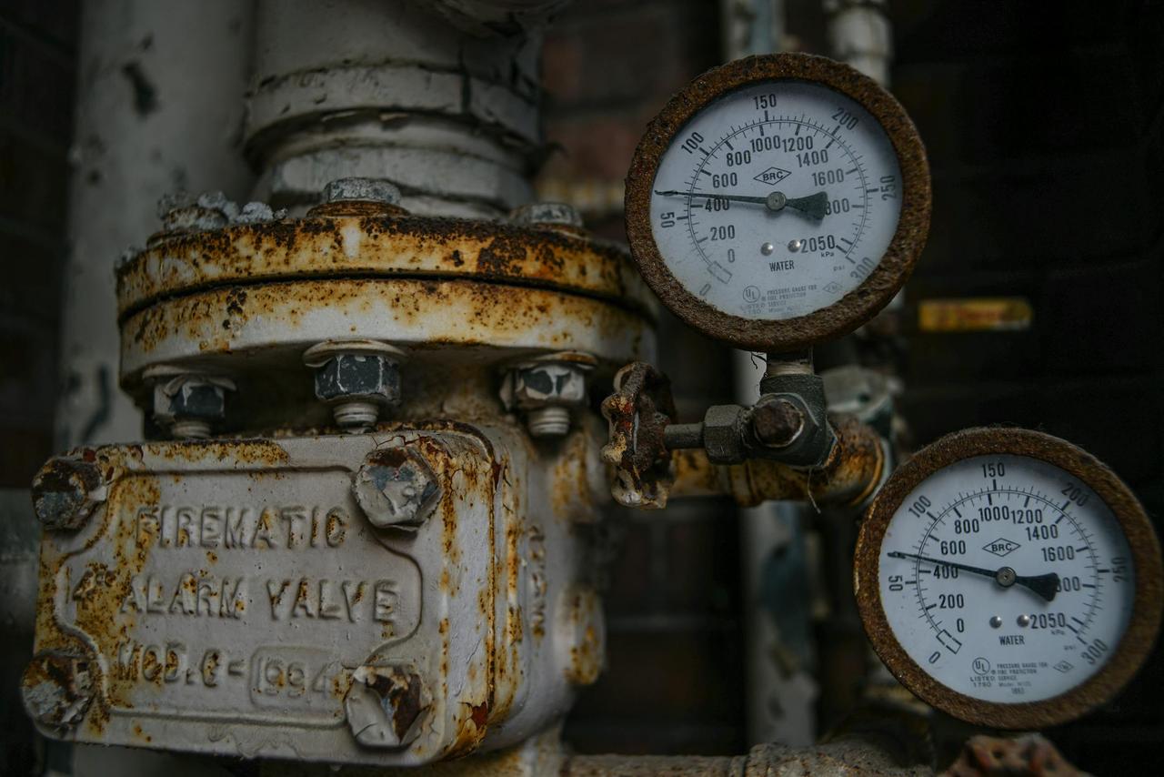 Close-up of an aged and rusted pressure valve with gauges showing readings.