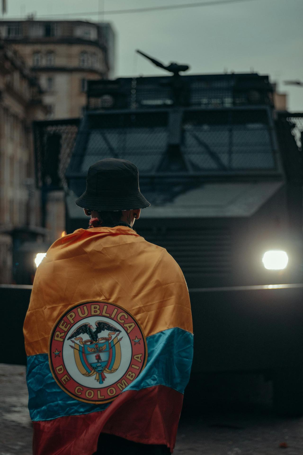 A person wrapped in Colombia's flag stands in front of an armored vehicle during a protest in Bogotá.