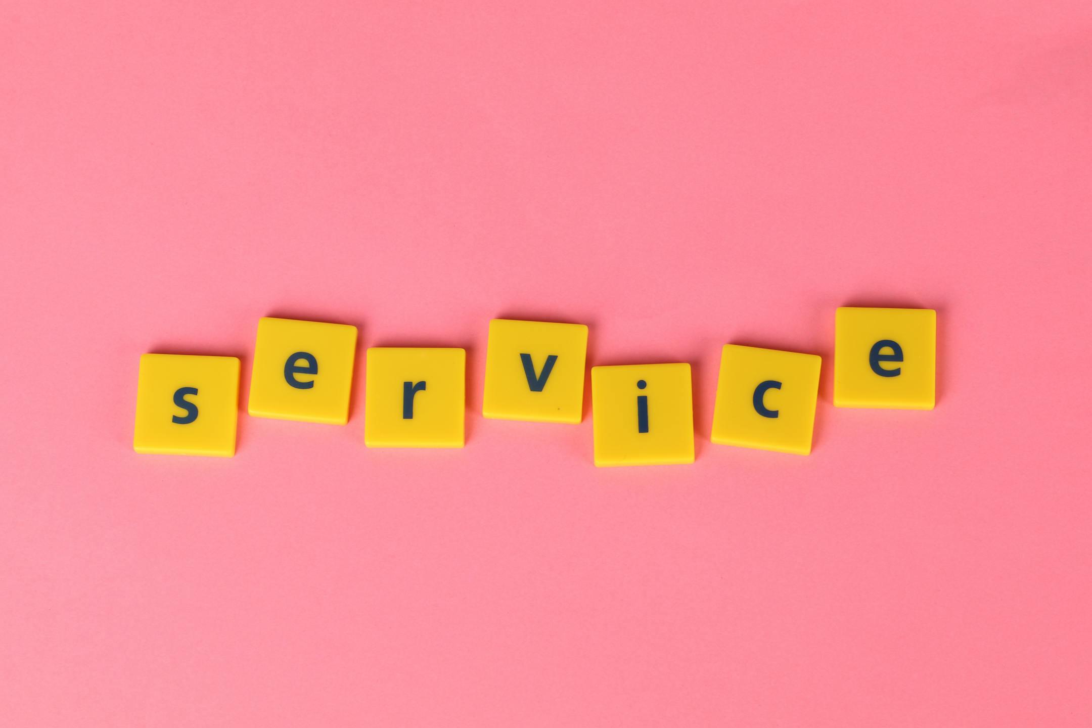 Yellow tiles spelling the word 'service' on a pink background, visually appealing design.