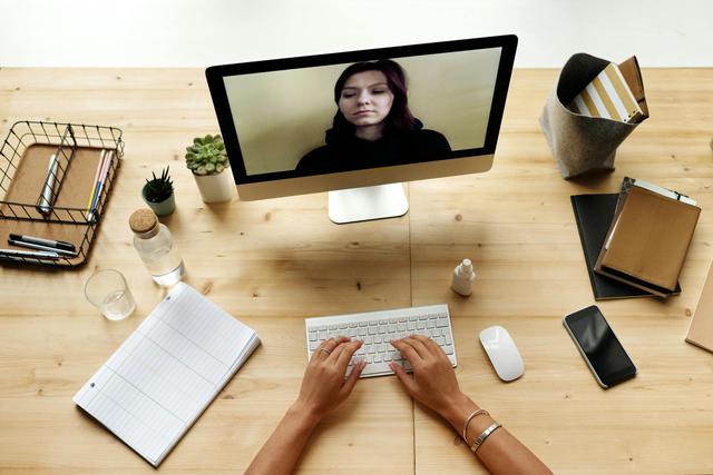 A person working from home using a computer for a video call, depicting a modern remote office setup with excellent corporate compliance.