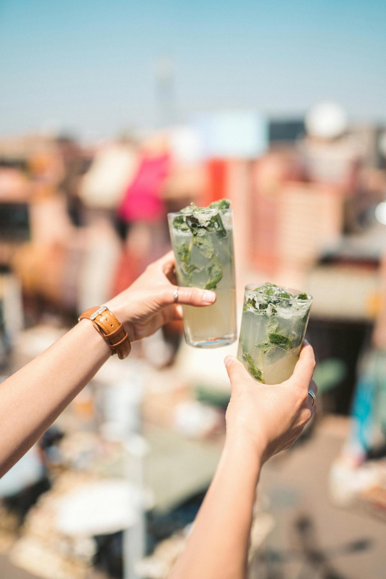 Two people celebrating with mojitos at a rooftop party, a vibrant outdoor scene.