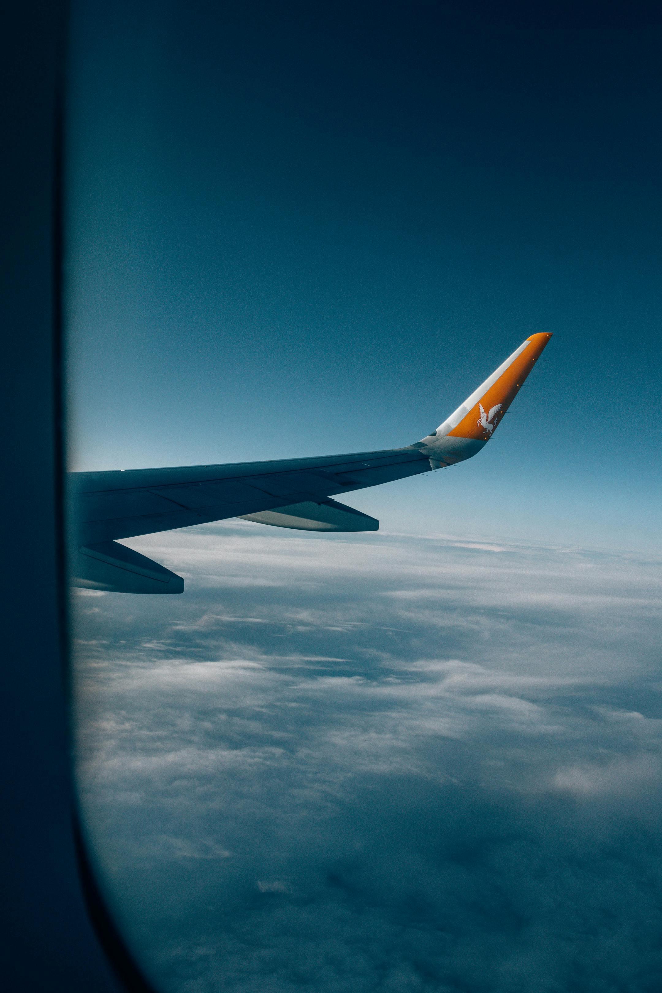 A serene view of an airplane wing above the clouds at daylight.