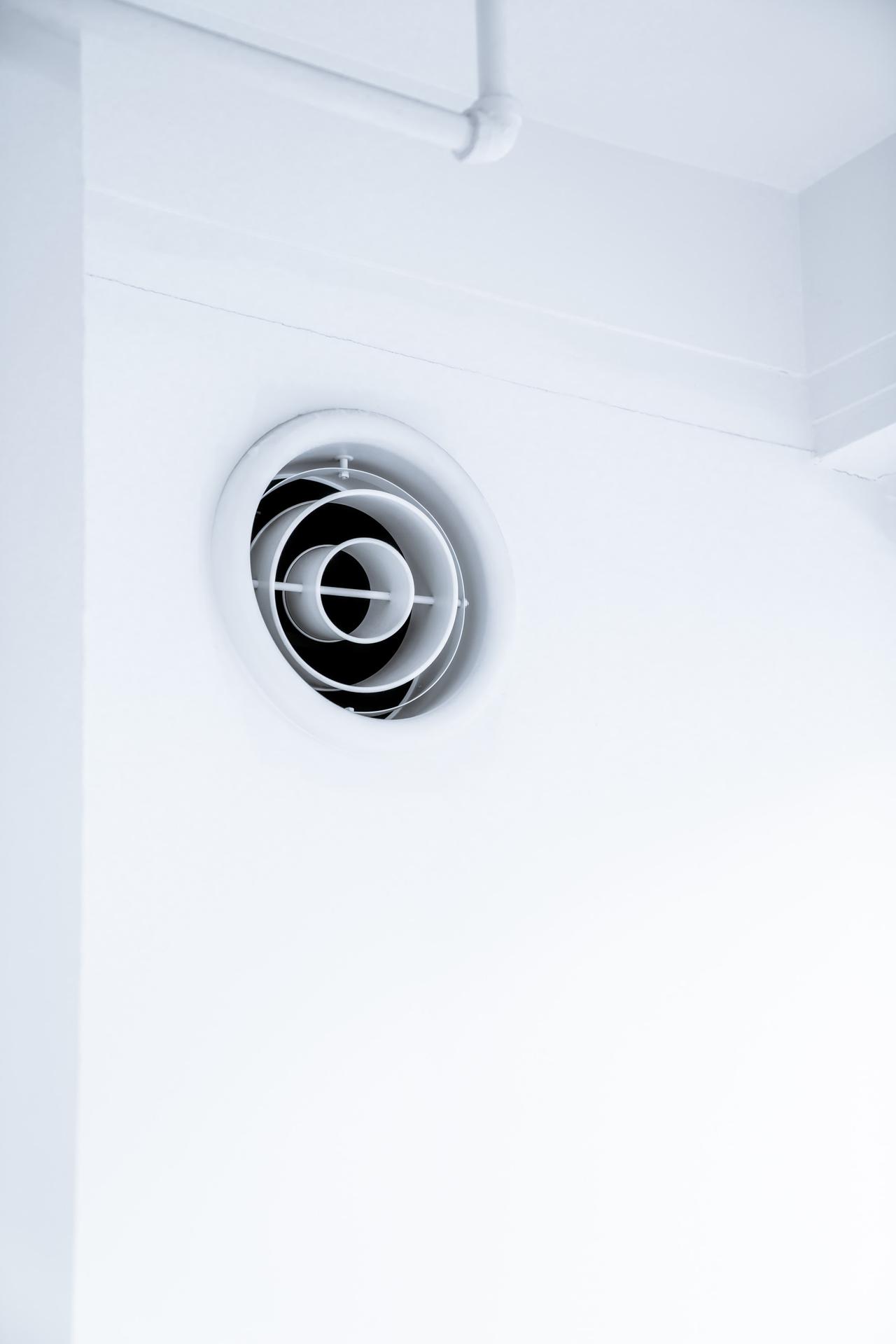 Circular shapes of an air vent on a white wall.