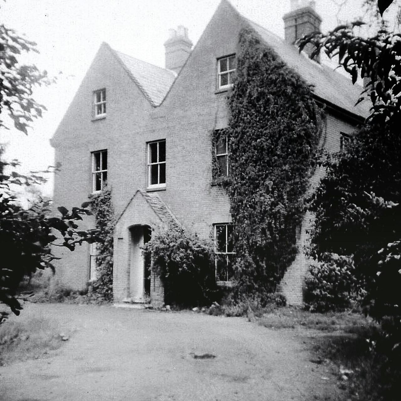Grayscale image of an old country house covered in ivy.