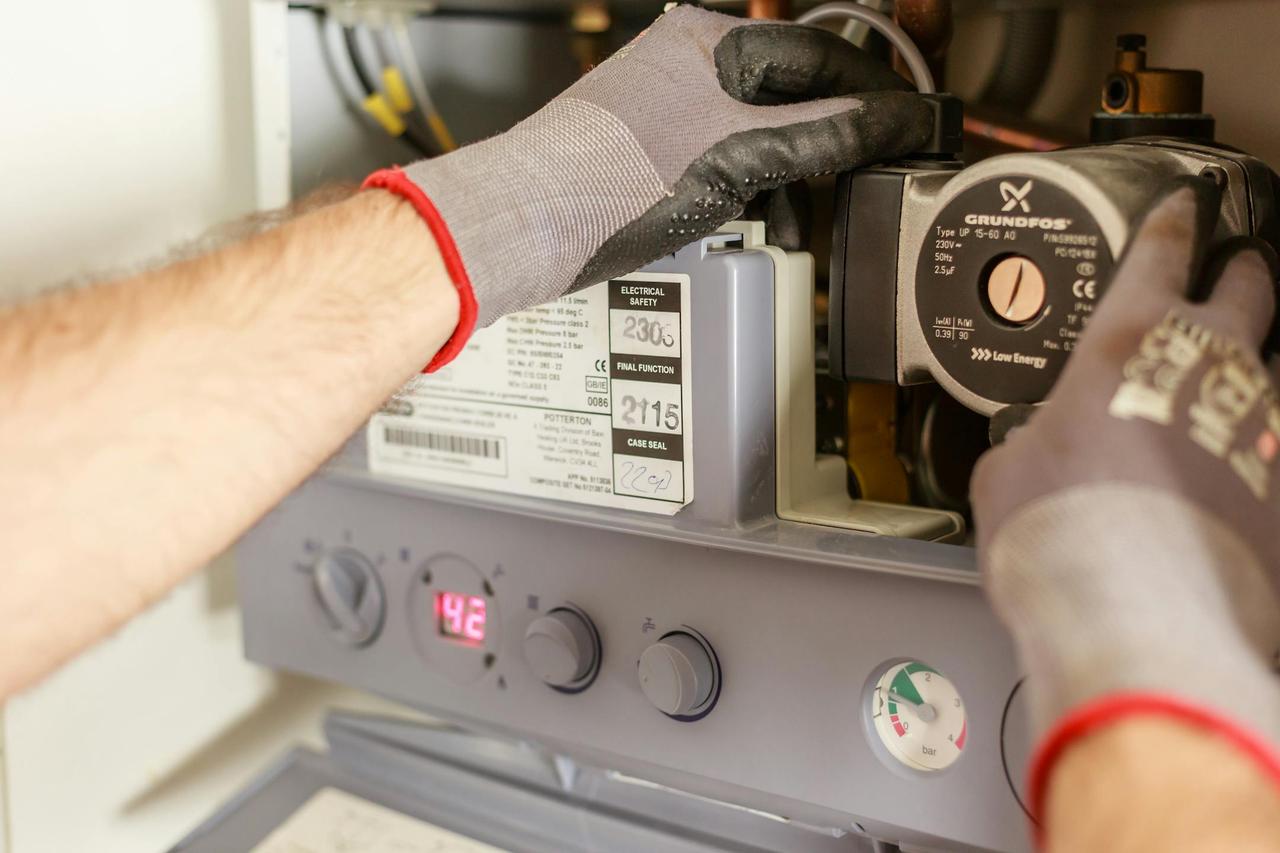 Close-up of hands adjusting a boiler system with precise instrumentation, showing maintenance work.