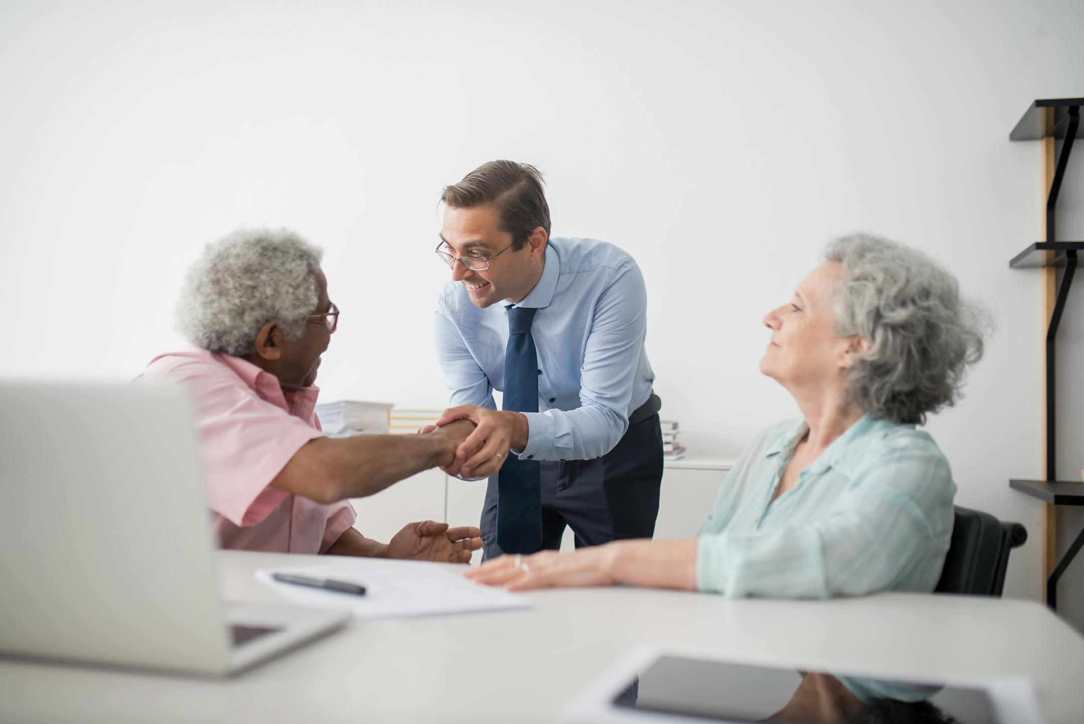 Business professional meeting with senior clients in an office setting, showcasing diversity and cooperation.