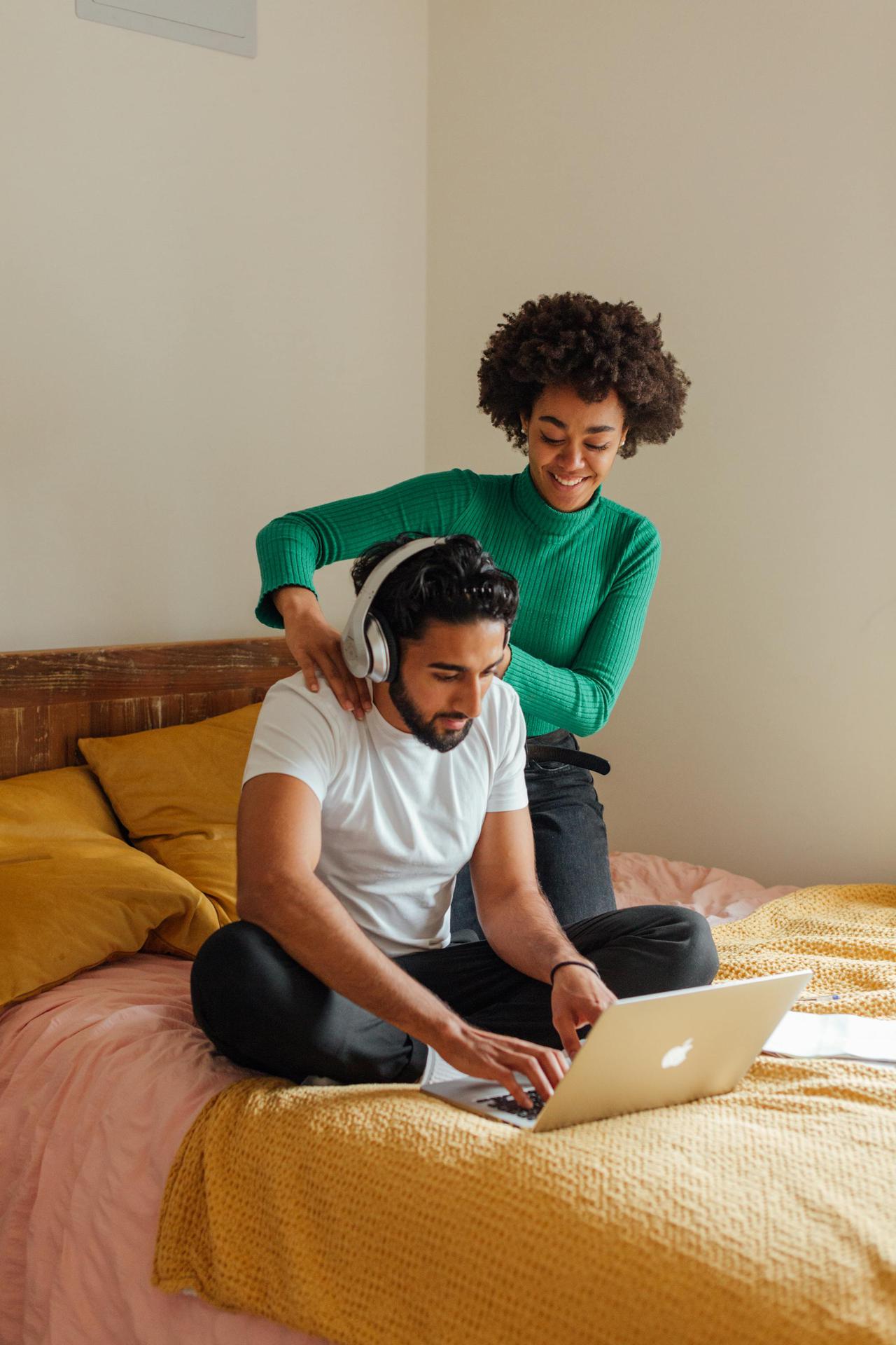 An interracial couple enjoying a work-from-home day with a massage in the bedroom.
