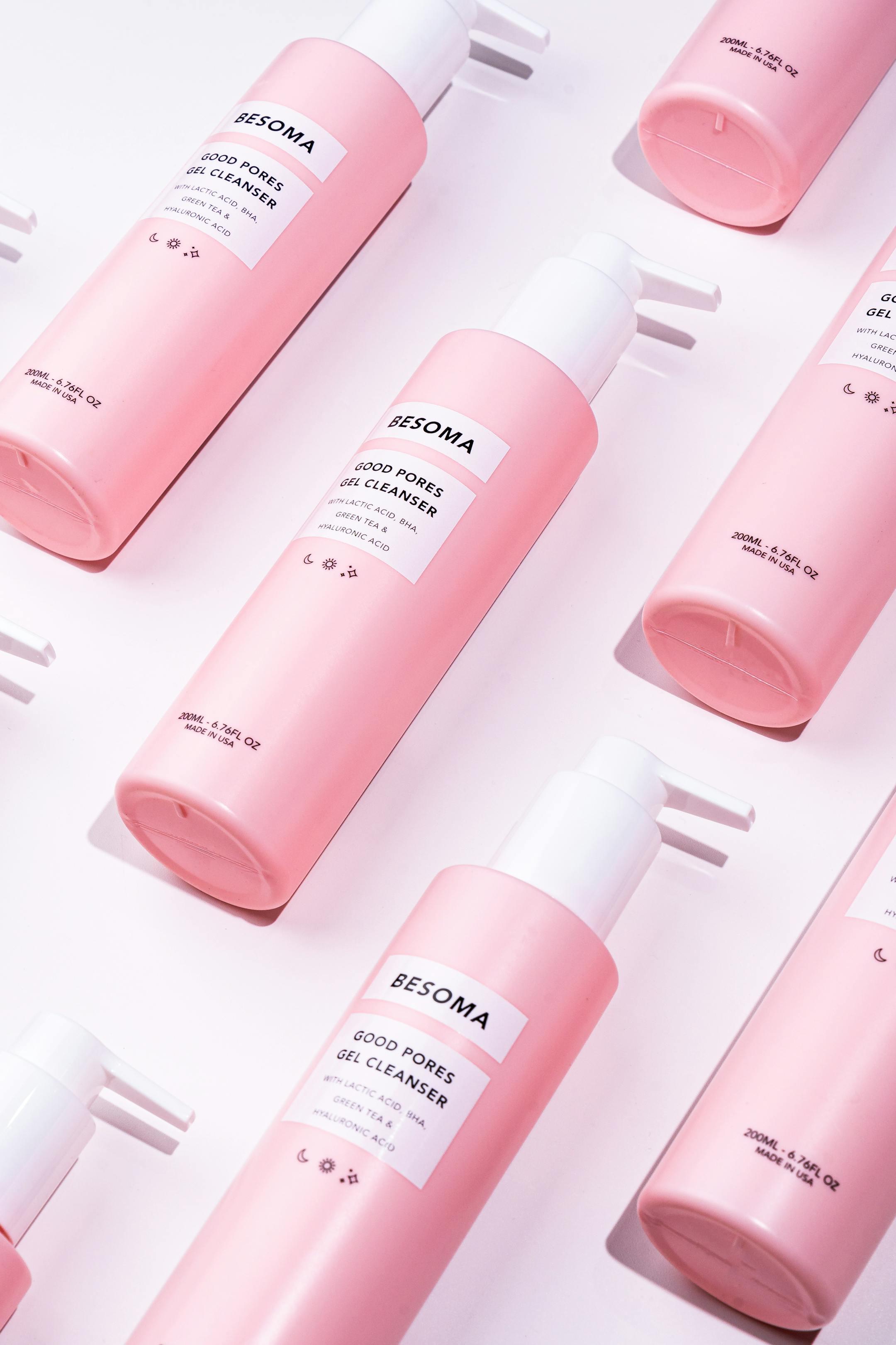 Stylish pink cosmetic bottles arranged in a flat lay on a white backdrop, ideal for beauty ads.