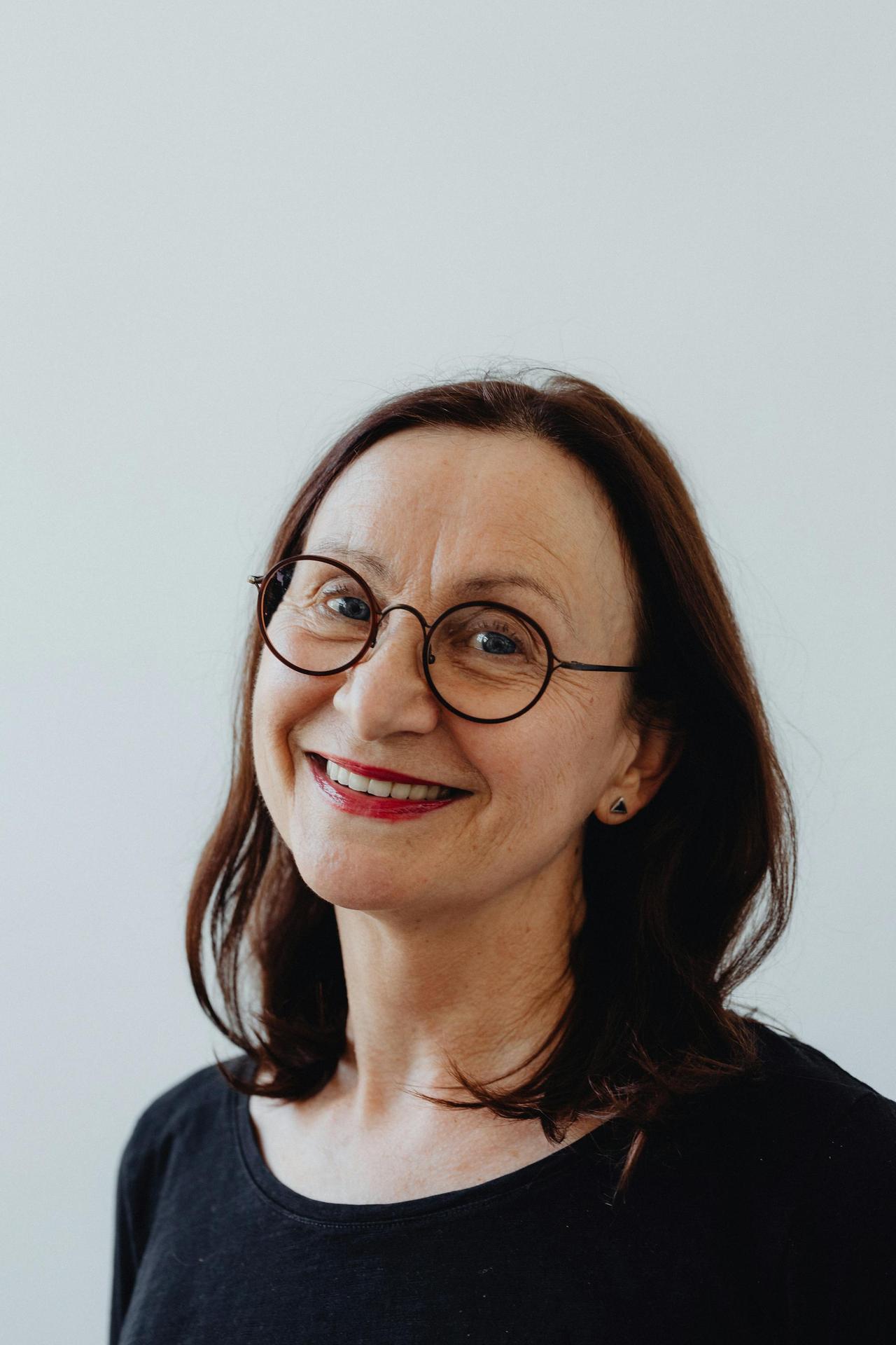 Portrait of a smiling senior woman wearing glasses on a white background.