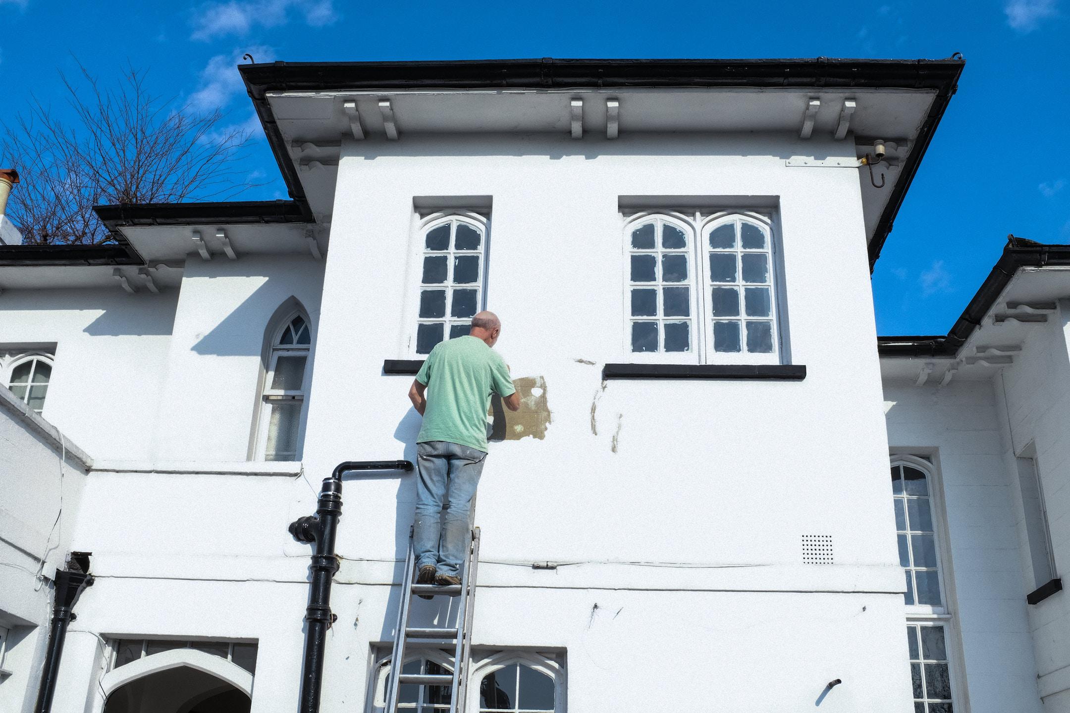 A man painting a house white - photo by @FlowClark - for more, visit: FlowClark.com