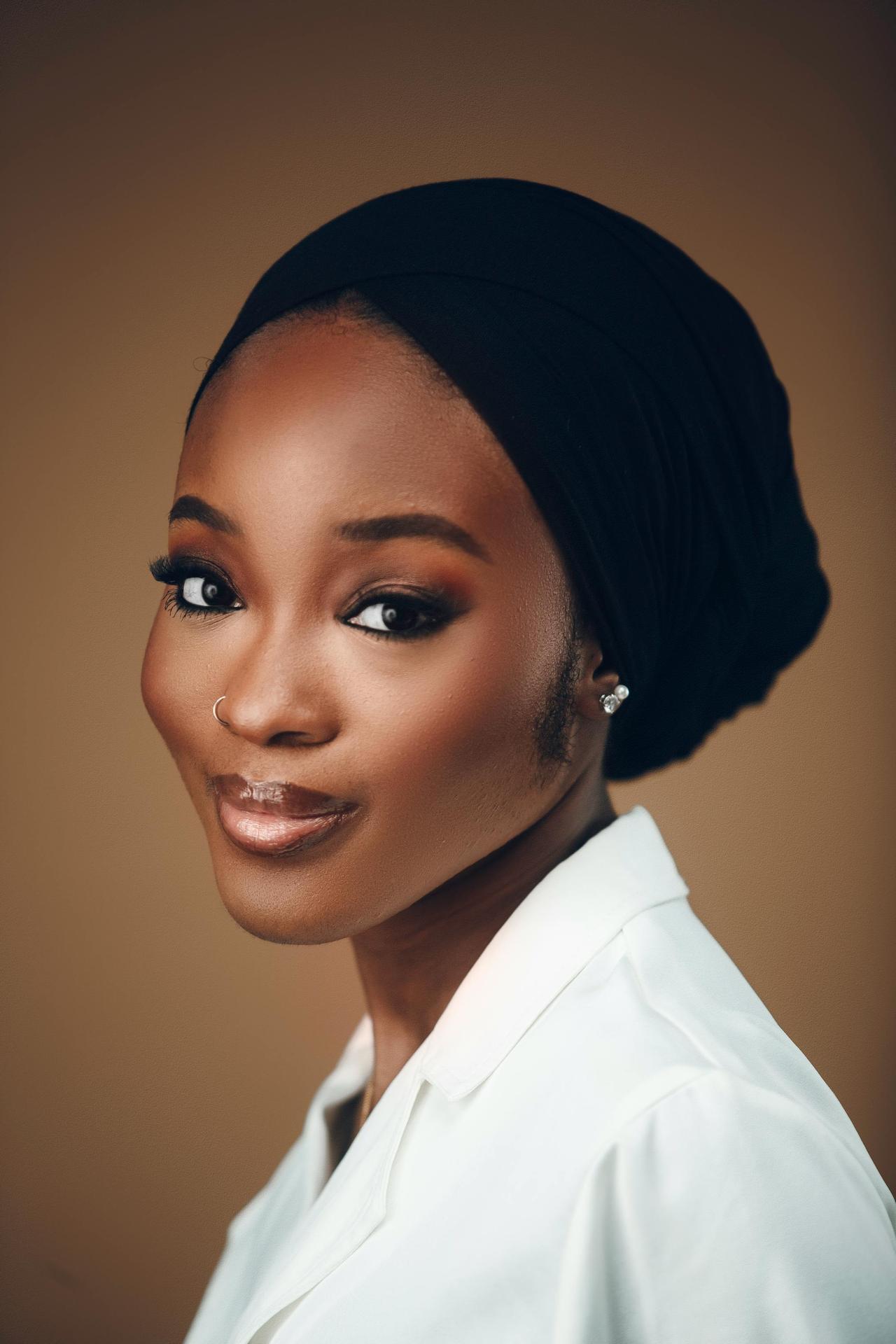 A stunning portrait of an elegant woman wearing stylish attire, captured indoors with warm lighting.