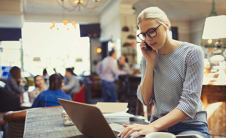 lady working on a laptop and talking on a cellphone
