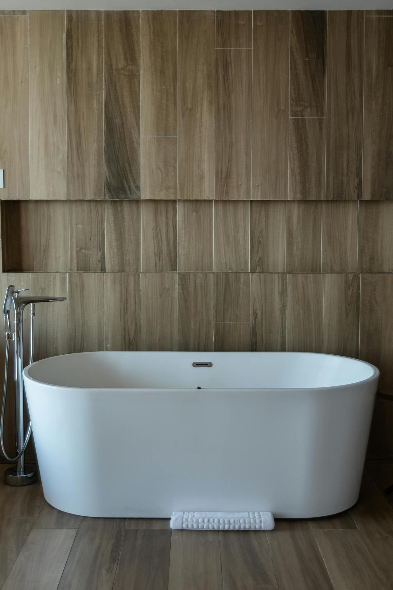 A stylish white bathtub in a contemporary spa-like bathroom with wooden decor.