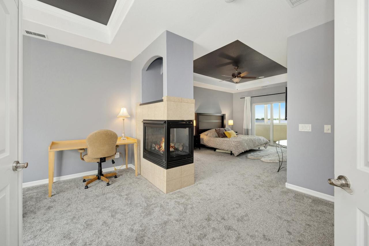 Elegant modern bedroom featuring a cozy fireplace and minimalist design with desk setup.