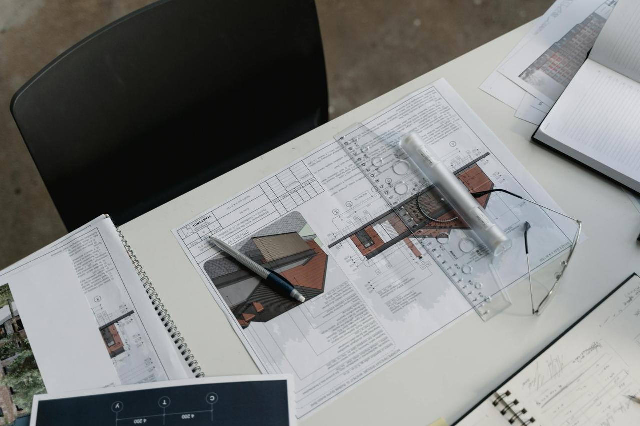 Top view of architectural blueprints and drafting tools on a workspace desk.
