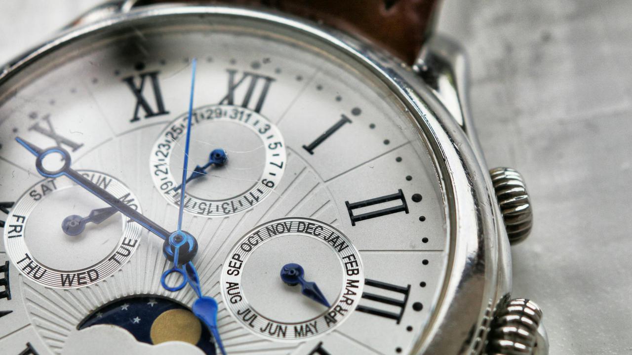 Detailed macro shot of an antique analog wristwatch with Roman numerals and calendar face.