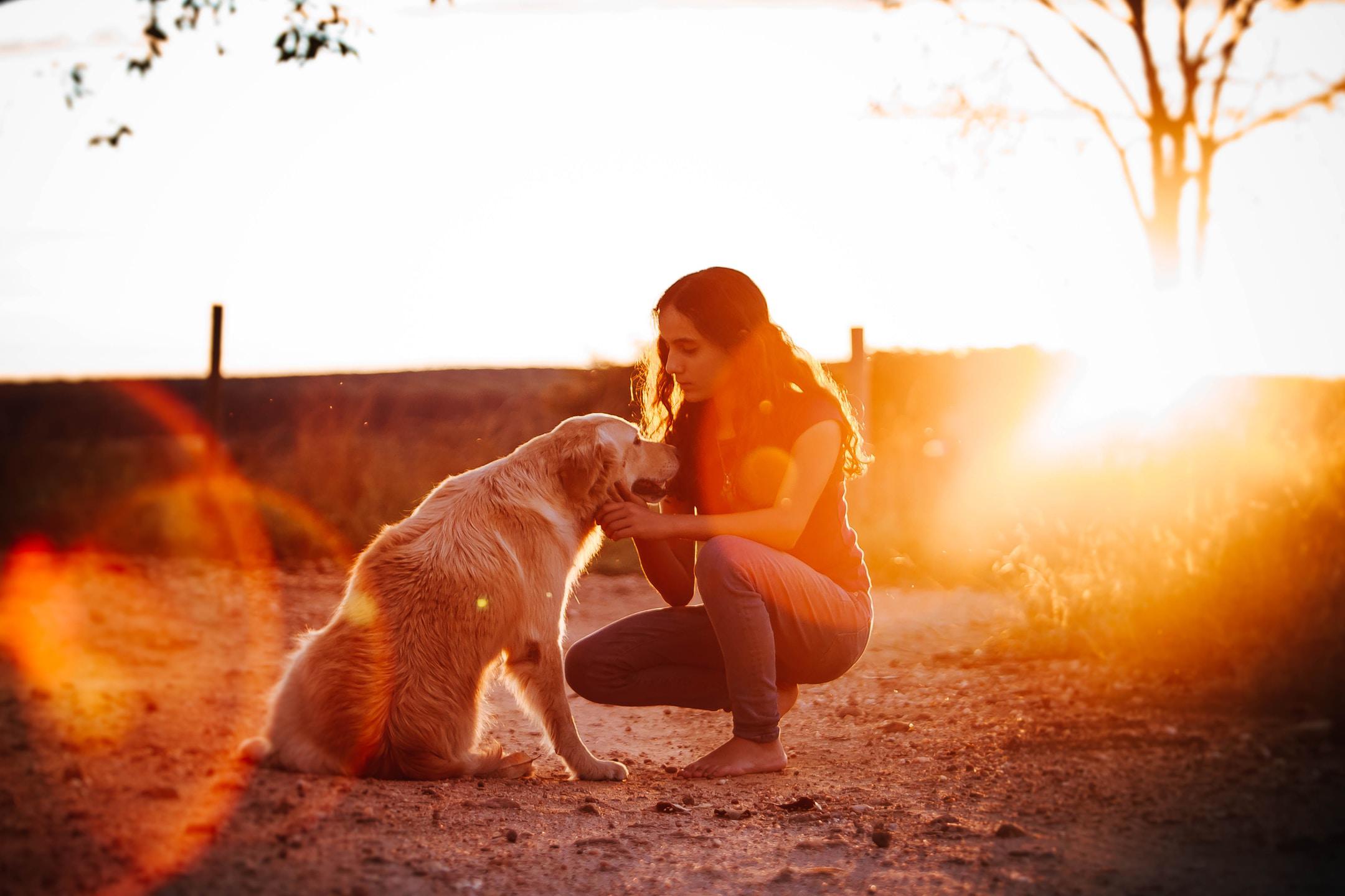 A girl kneeling down to pet her dog