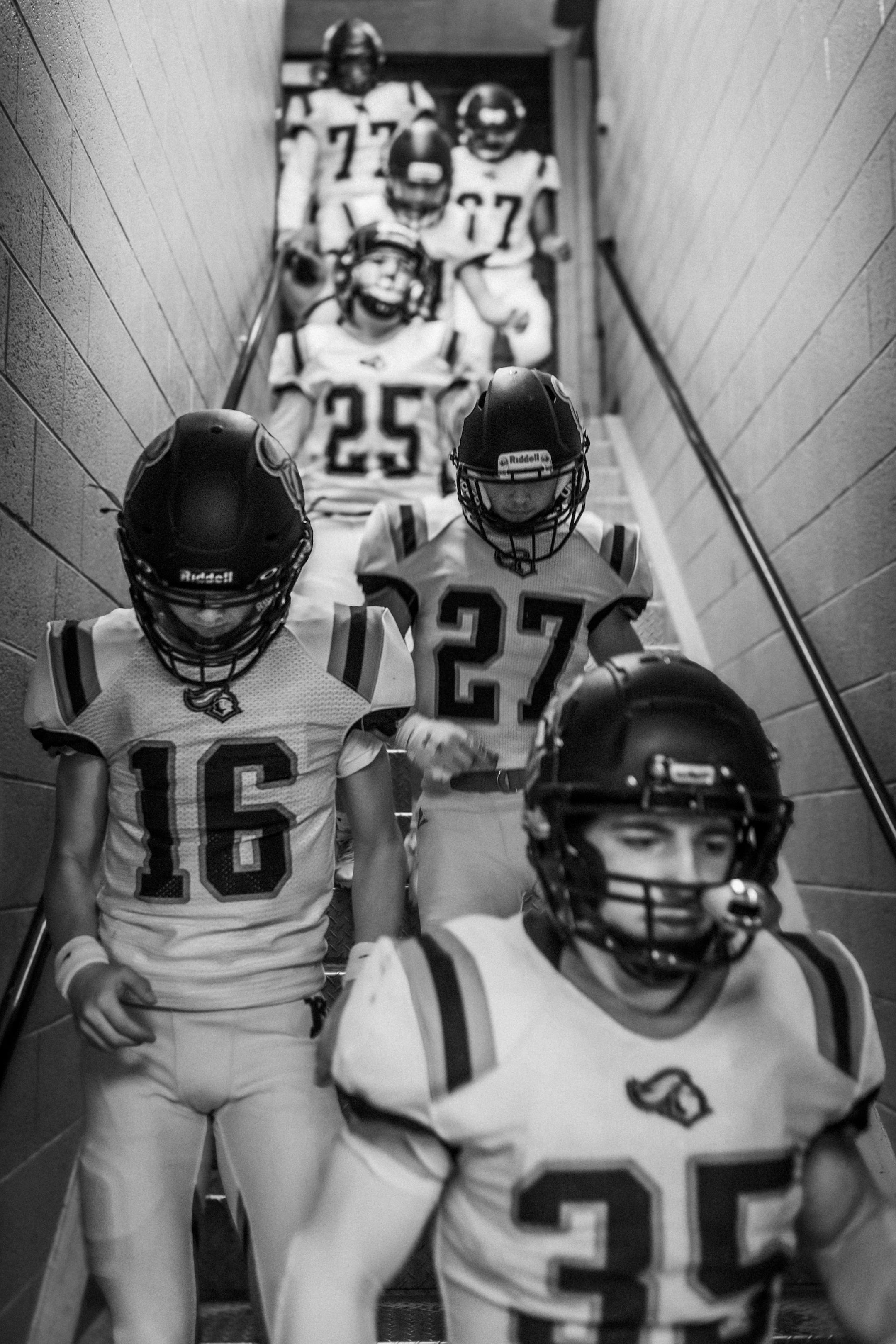 High school football players descending a staircase in uniforms, exuding team spirit and focus.
