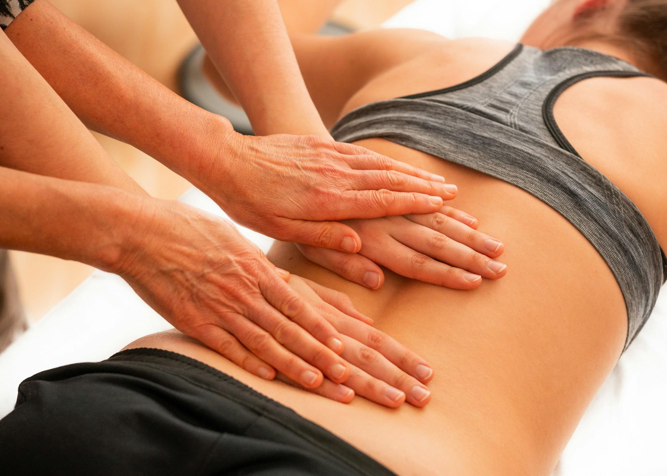 Ostheopathy with four hands on the back of a woman
