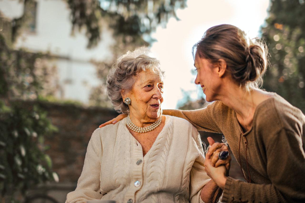 Elderly woman sitting and chatting with a companion carer.