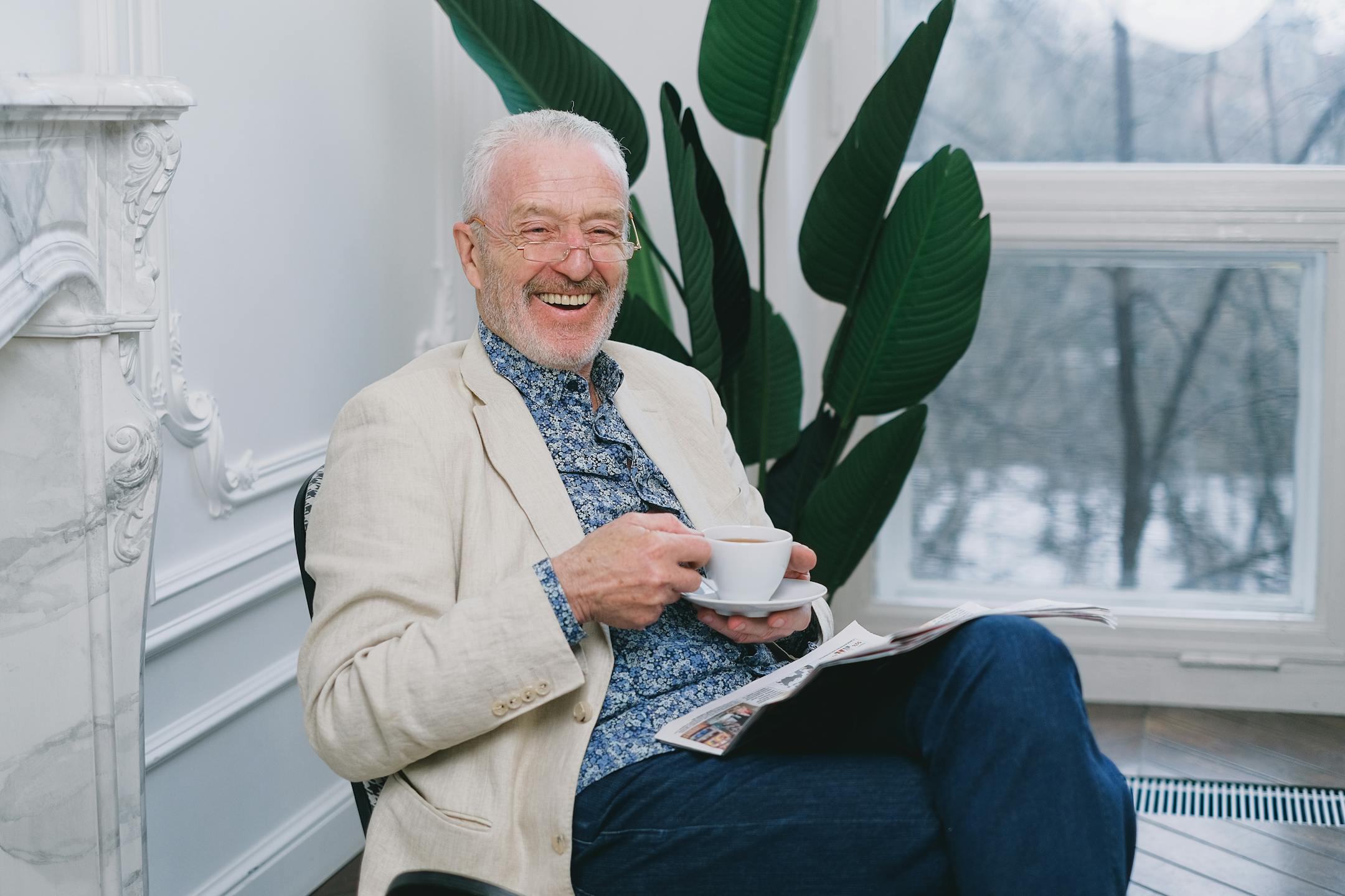 Cheerful senior man enjoying tea while relaxing indoors. Perfect depiction of leisure and contentment.