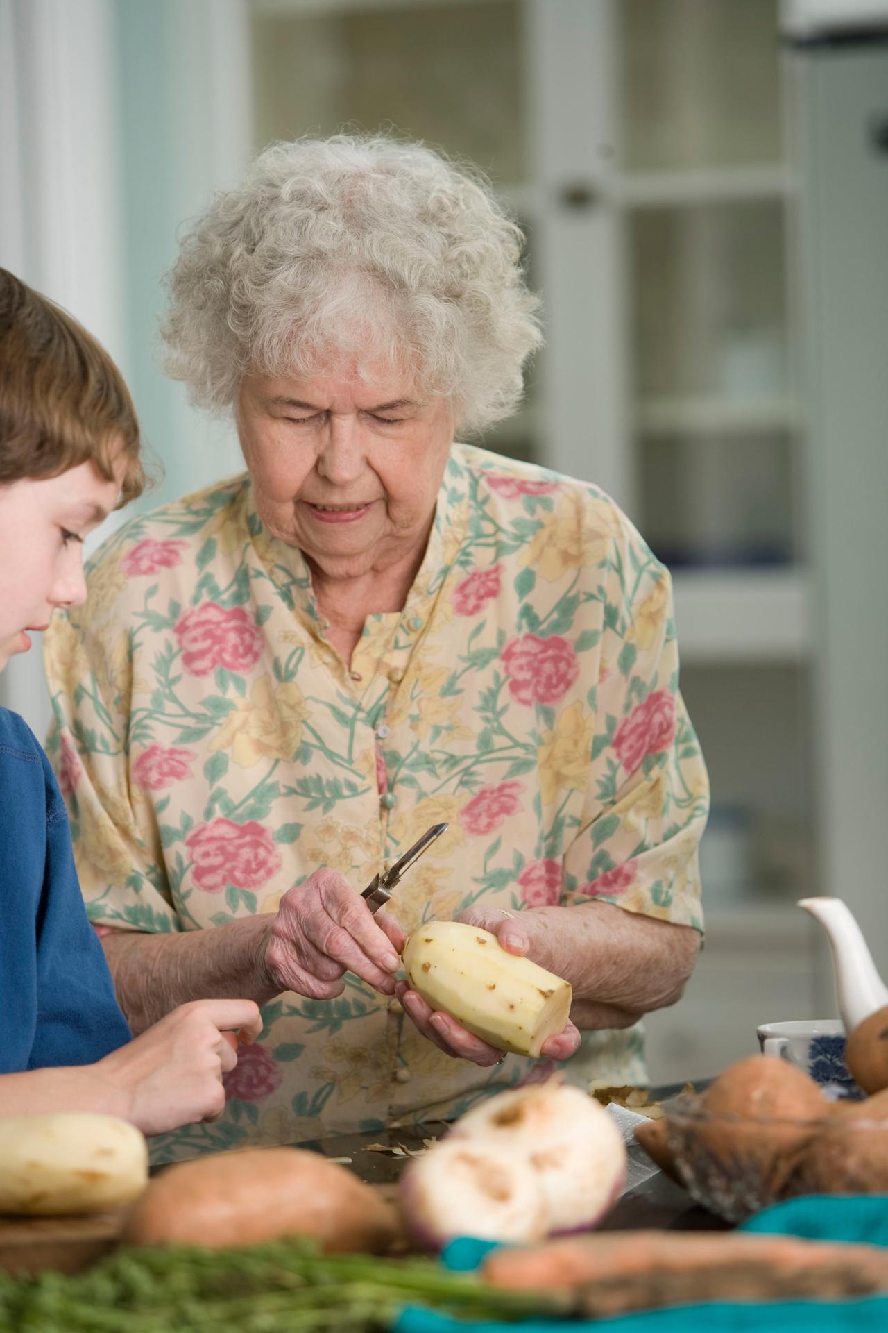 an elderly woman showing her grandson how to peel potatoes at a senior day care center in Dayton, Ohio
