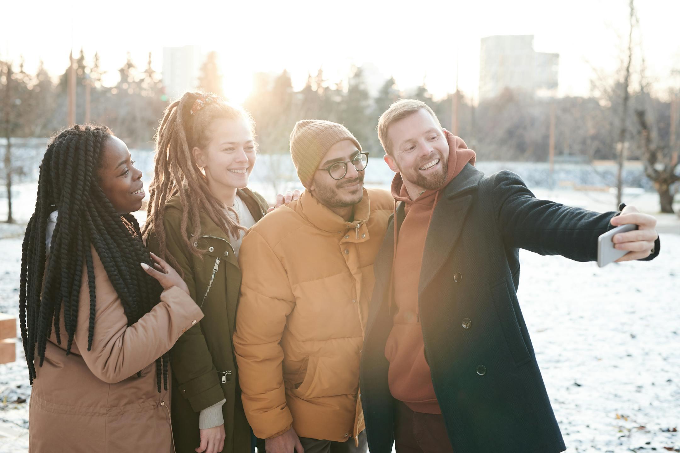Friends enjoying a snowy day taking a cheerful selfie outdoors in a park.
