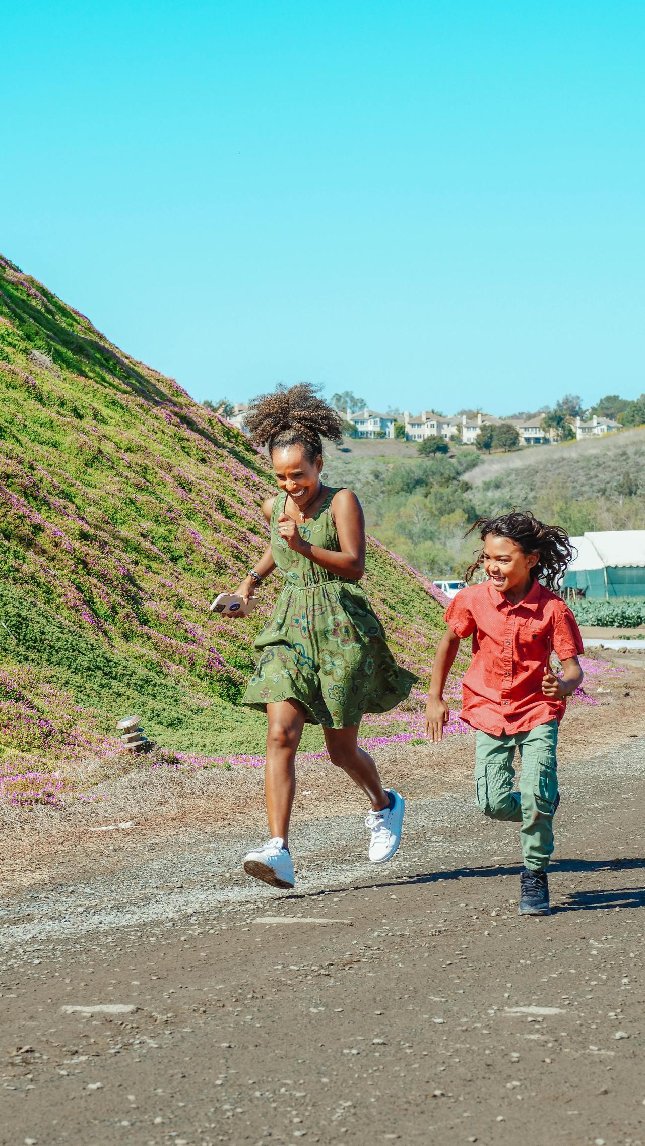 Two happy children running together in a green landscape, enjoying a sunny day.