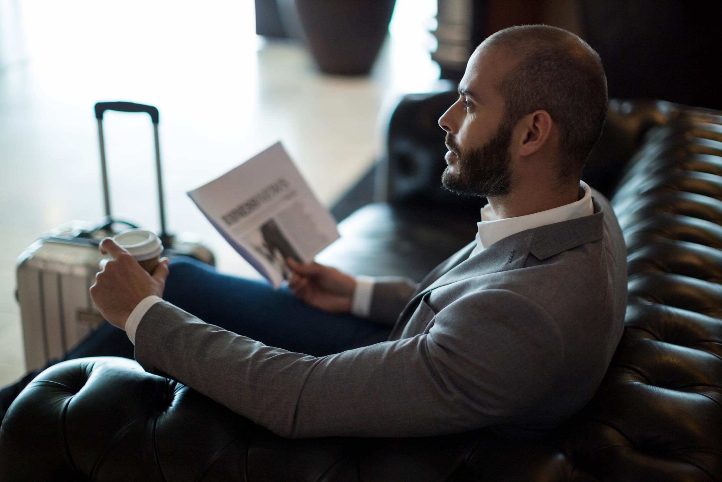 thoughtful-businessman-holding-newspaper-coffee-cup-waiting-area.jpg