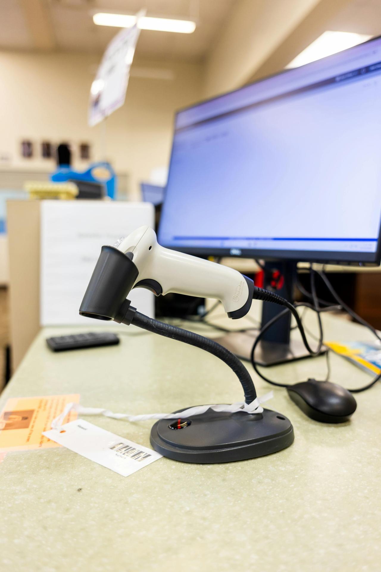 Close-up of a barcode scanner on an office desk with a computer screen in a modern workspace.