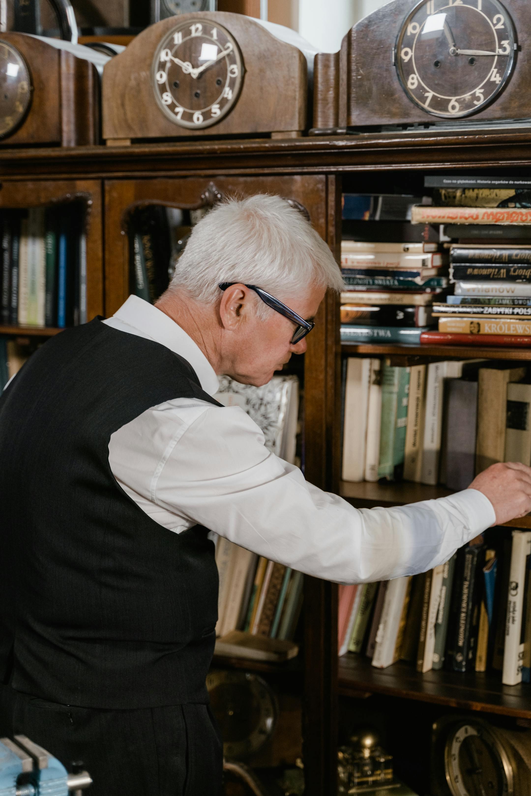 Elderly man choosing books from an antique bookshelf. Elegant and educational setting.