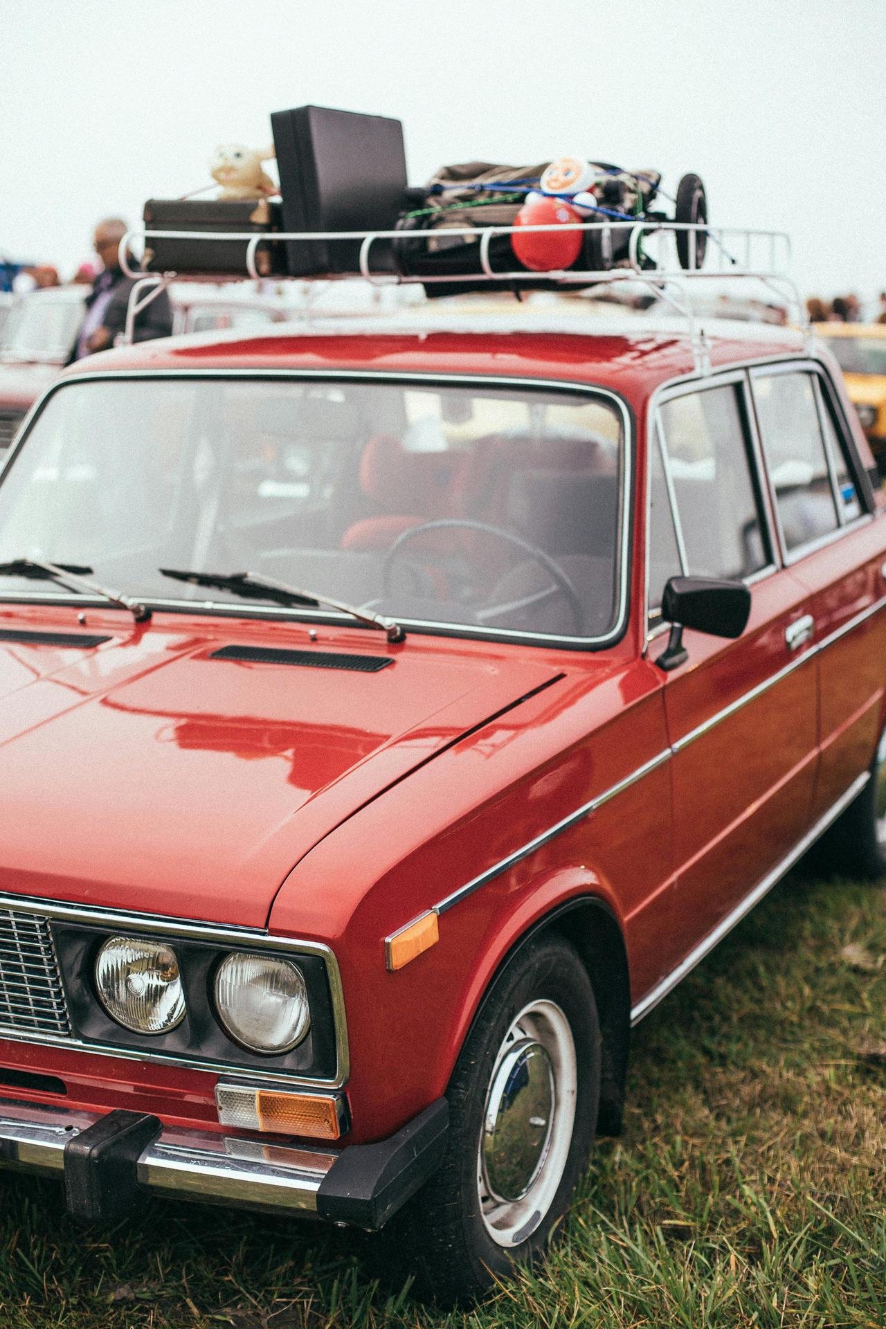 A classic red Lada with a roof luggage rack packed for travel, parked outdoors.