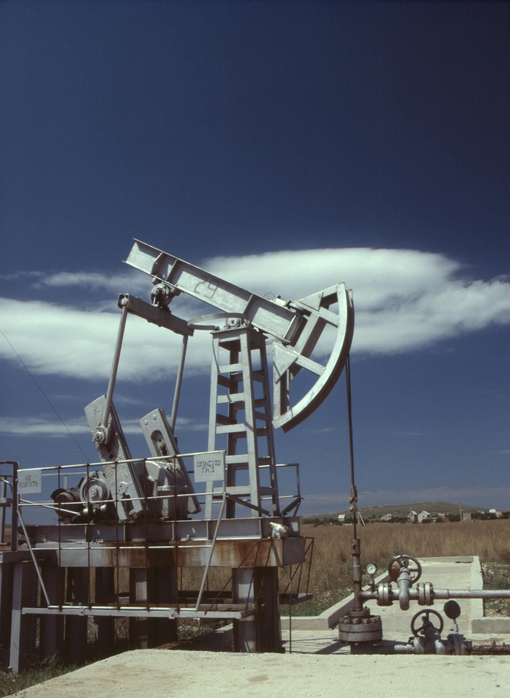 Oil pumpjack in operation against clear blue sky, highlighting industrial energy production.