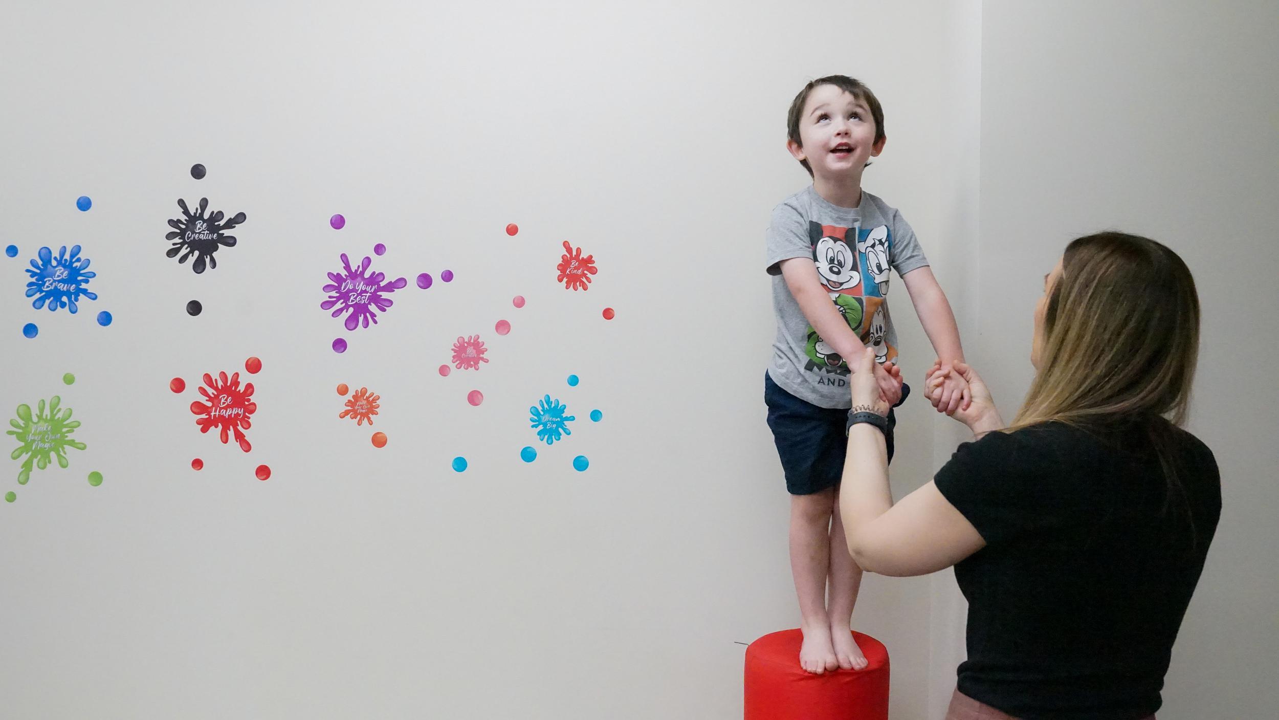 Child holding hands with occupational therapist during play-based therapy, Kansas City