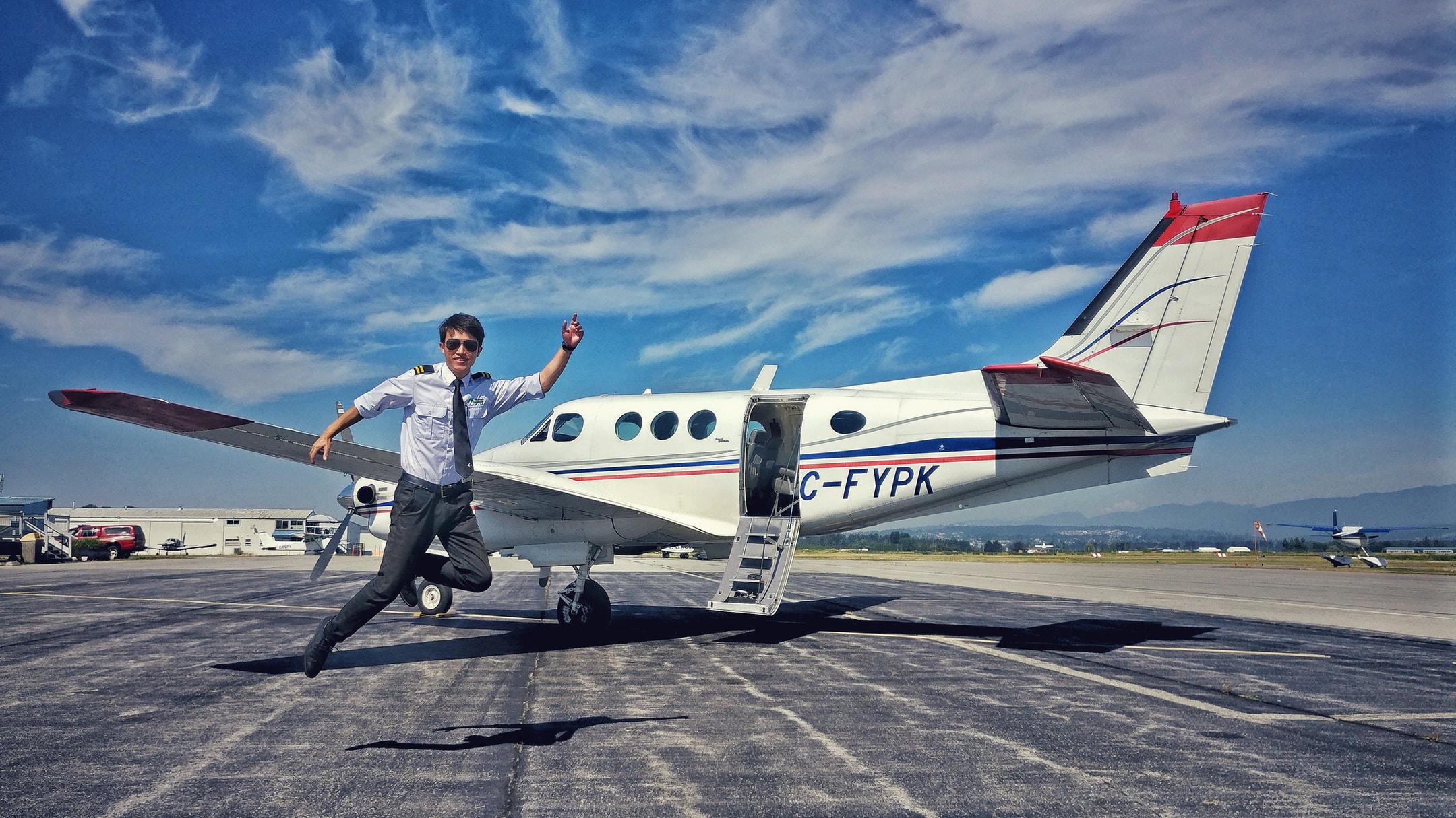 Image of a man in front of a private plane who's leaping for joy because he did English aviation training for a fast PPL and CPL.