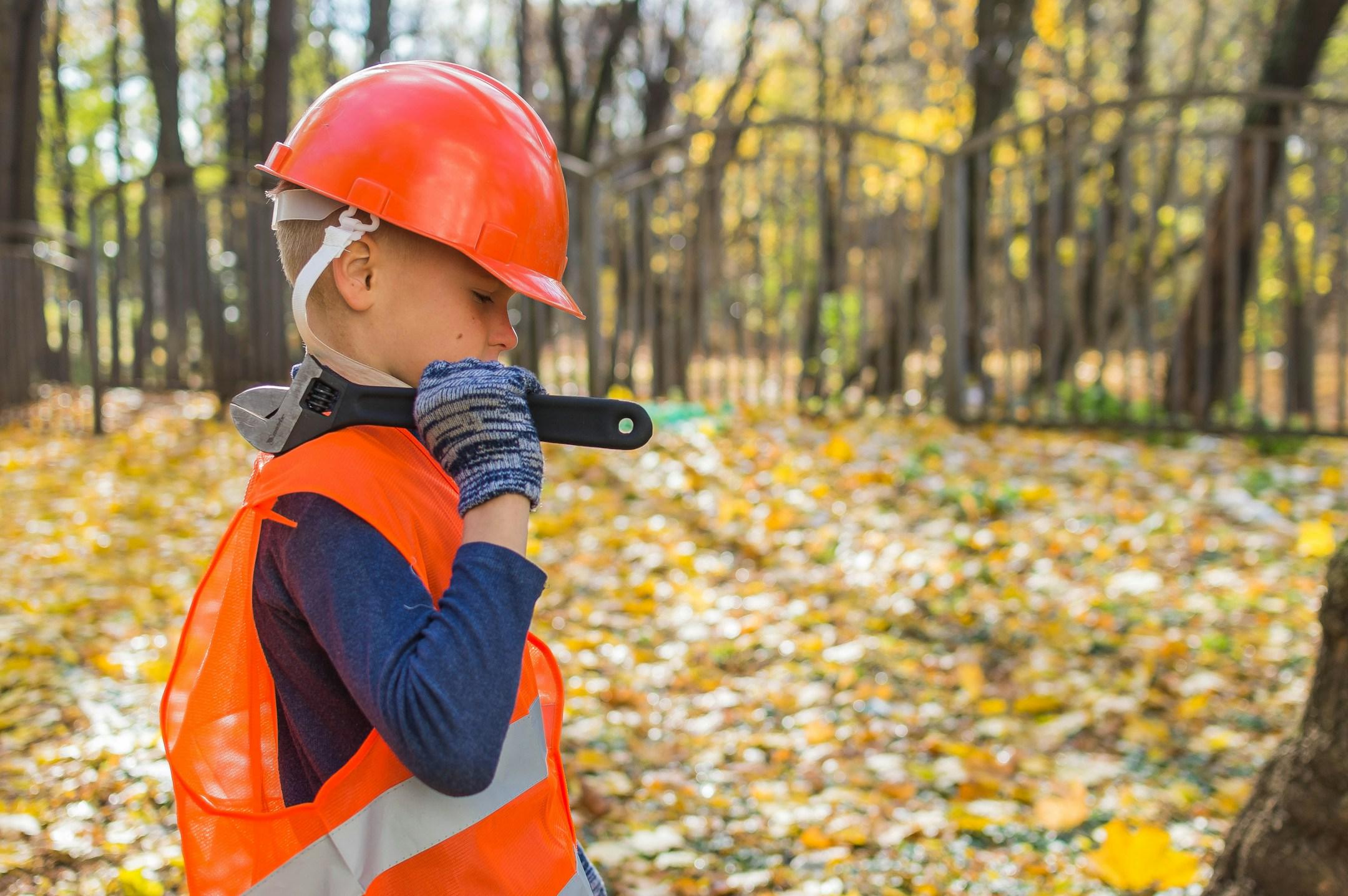 a boy dressed as a working man in a hard hat with a wrench
