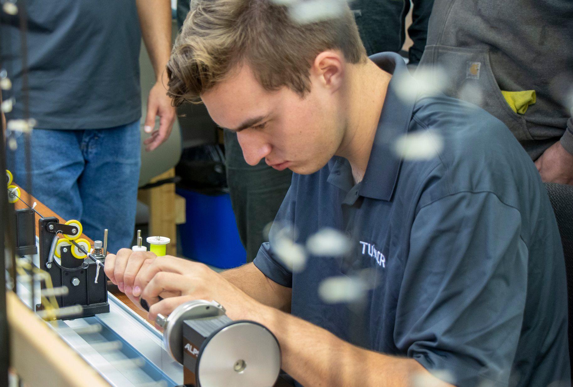 Custom Rod builder staring intently at a custom fishing rod he is wrapping