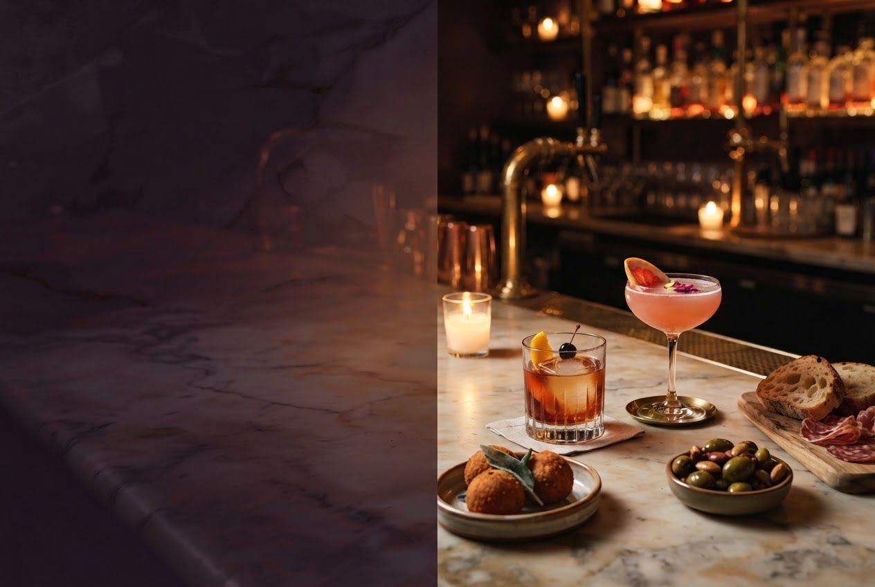 A candlelit cocktail and small plate on a marble bar, with brass shelves behind.