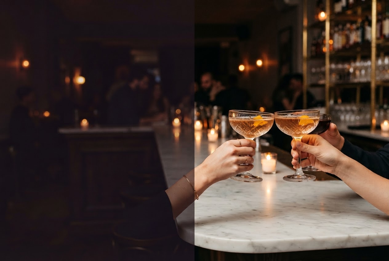 Guests raising cocktail coupes above a candlelit marble table with a small plate of bites.