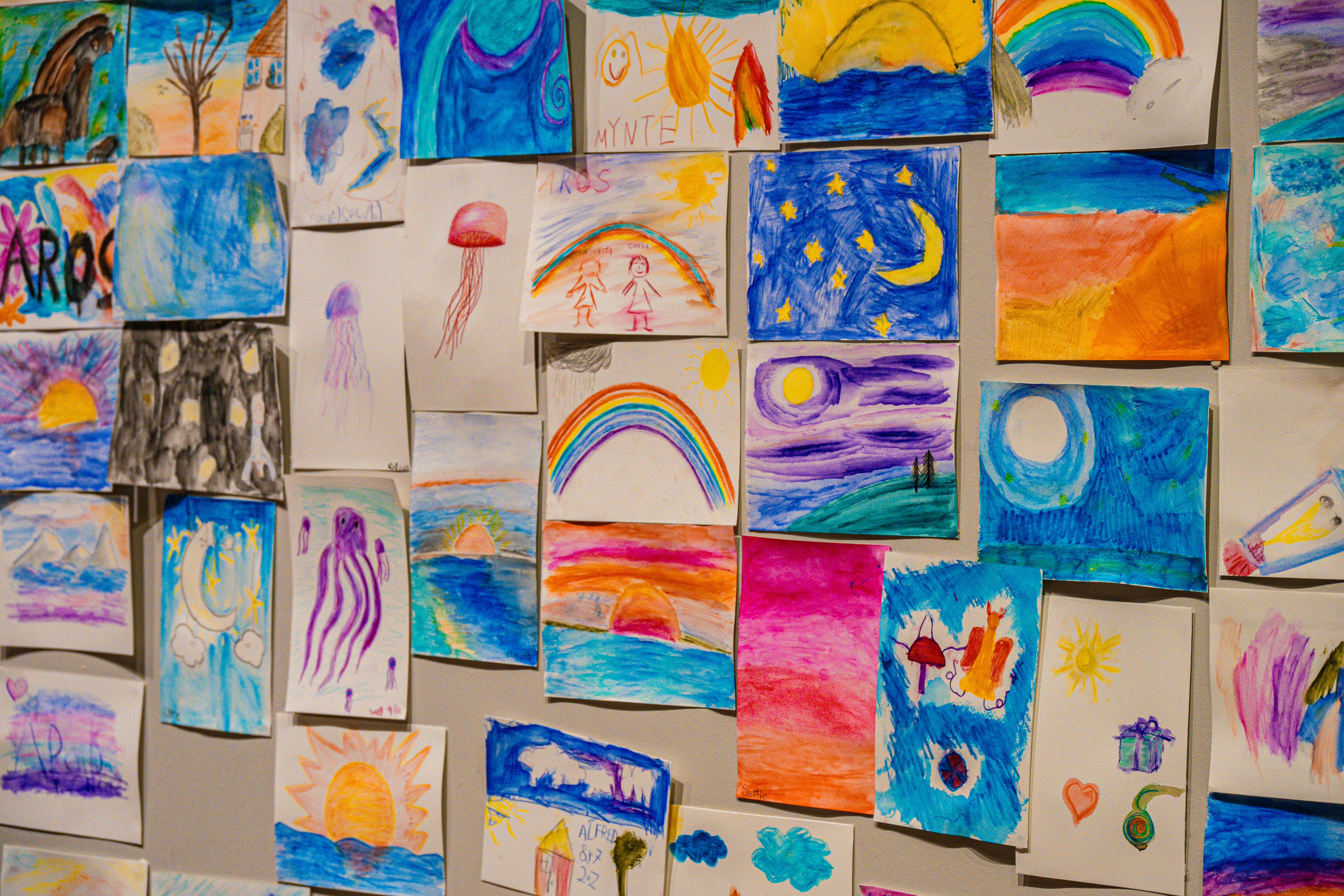 Collection of colorful children's drawings on a wall