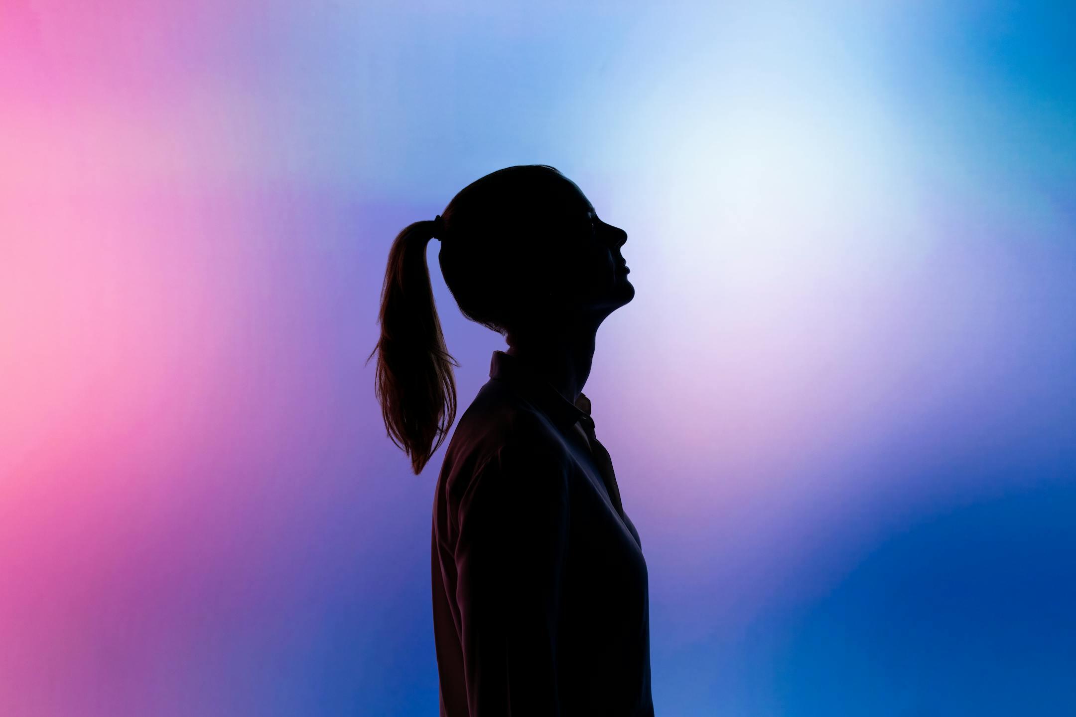 Artistic silhouette of a woman in ponytail against a vibrant gradient background.