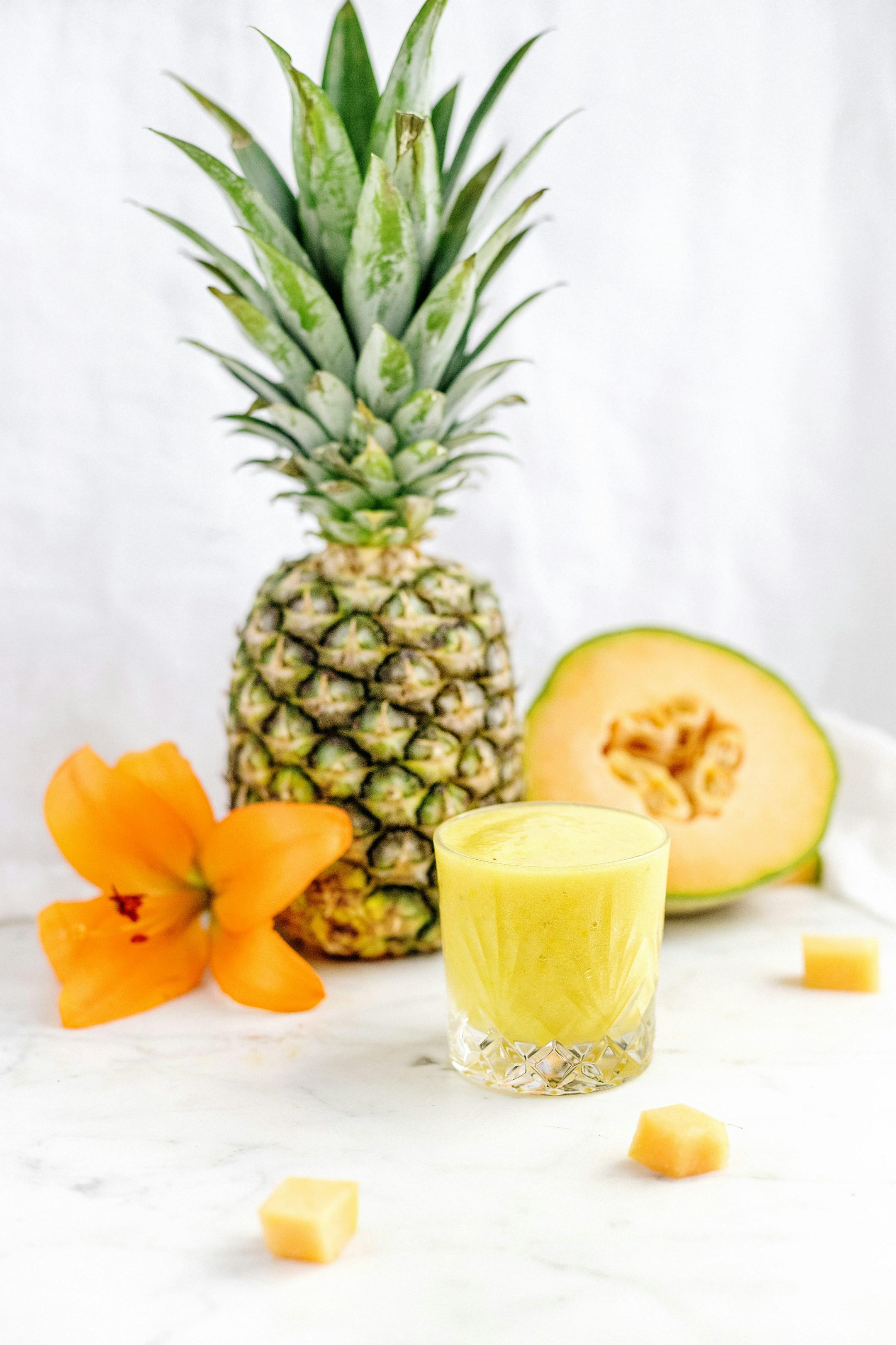 Gorgeous pineapple and cantaloupe smoothie on white marble dripping in the morning sunlight. 
