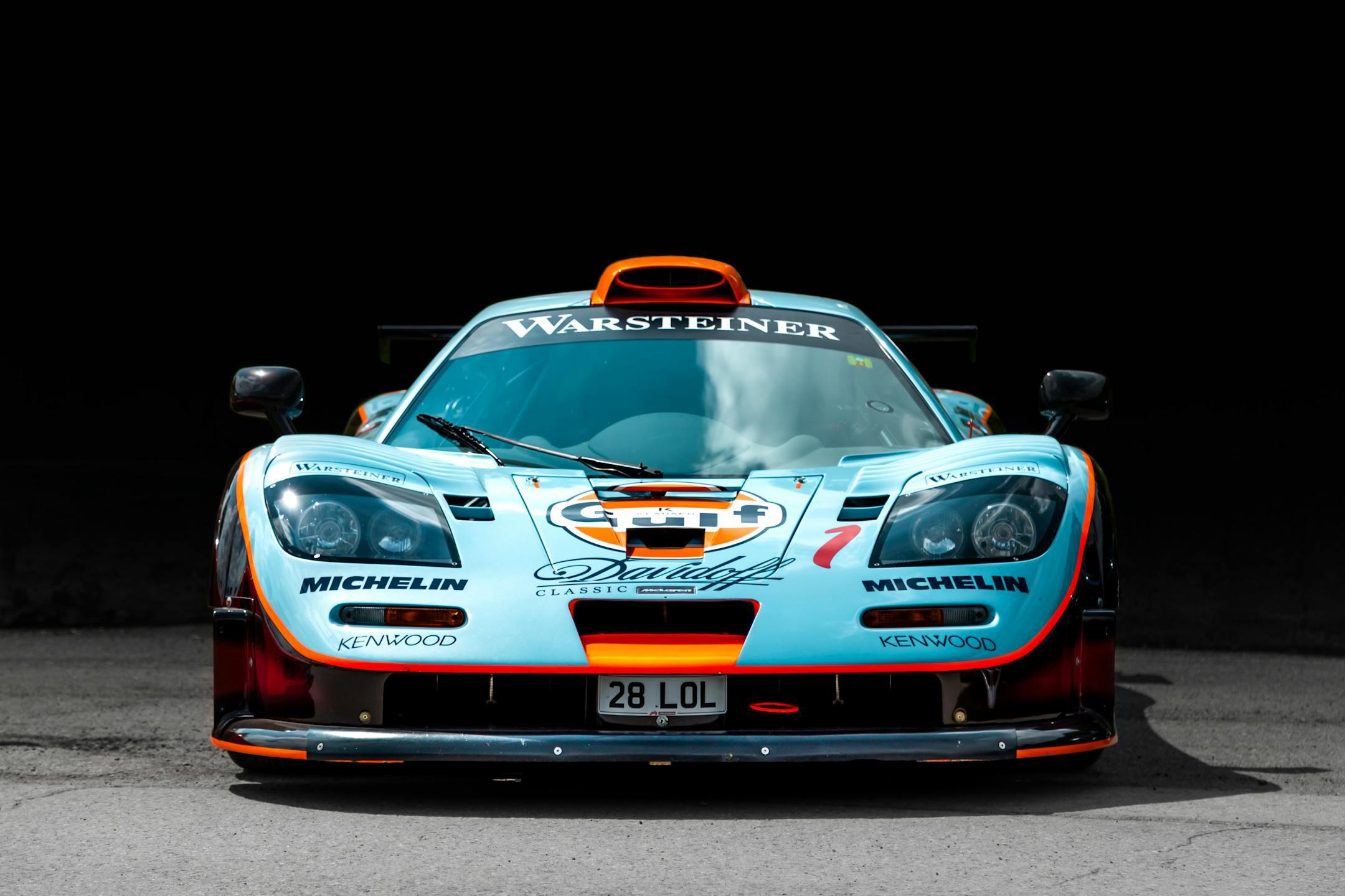 Front view of a classic McLaren racing car in vibrant colors against a dark backdrop.