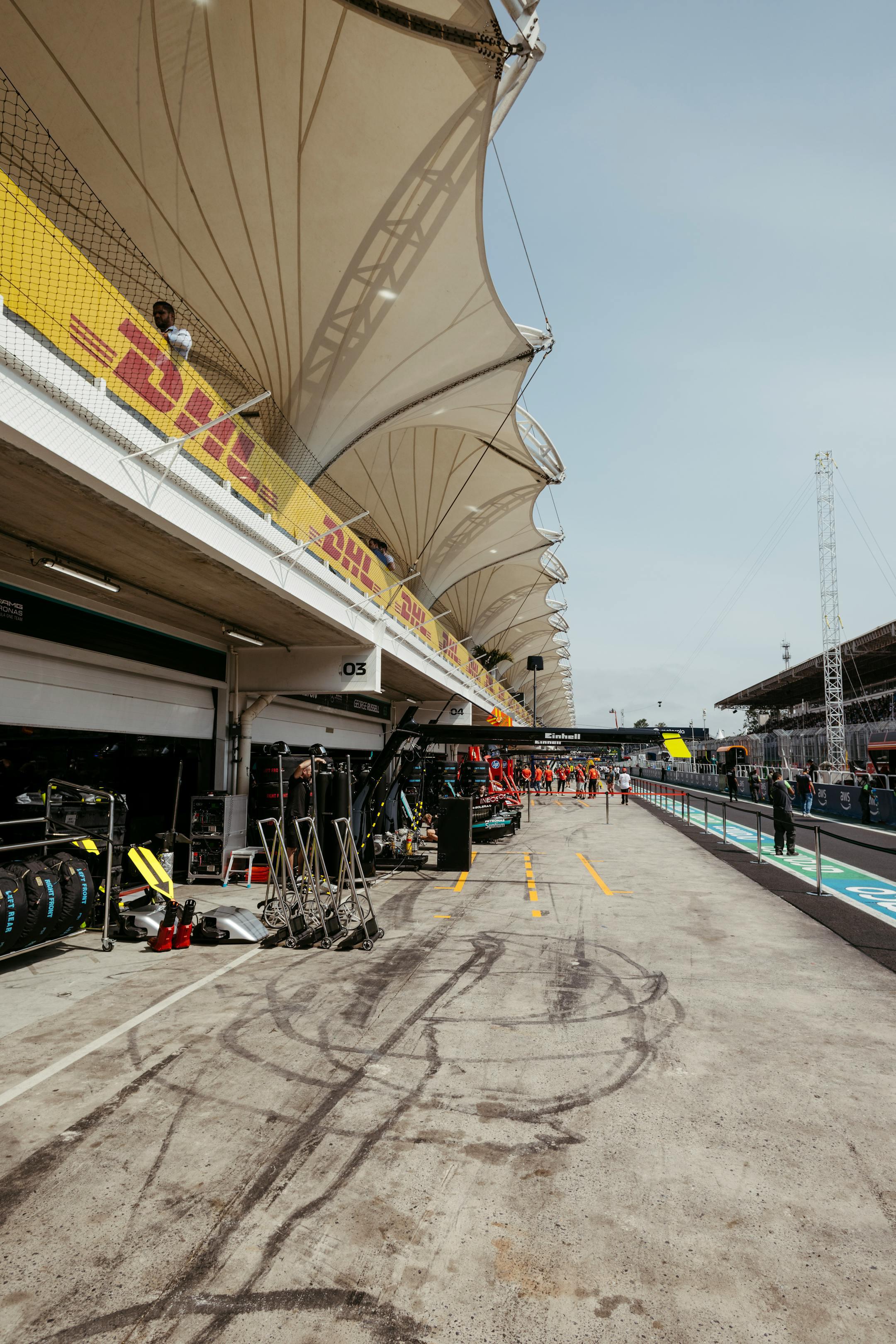 A bustling Formula One pit lane with distinctive tented structures, ready for race activity.
