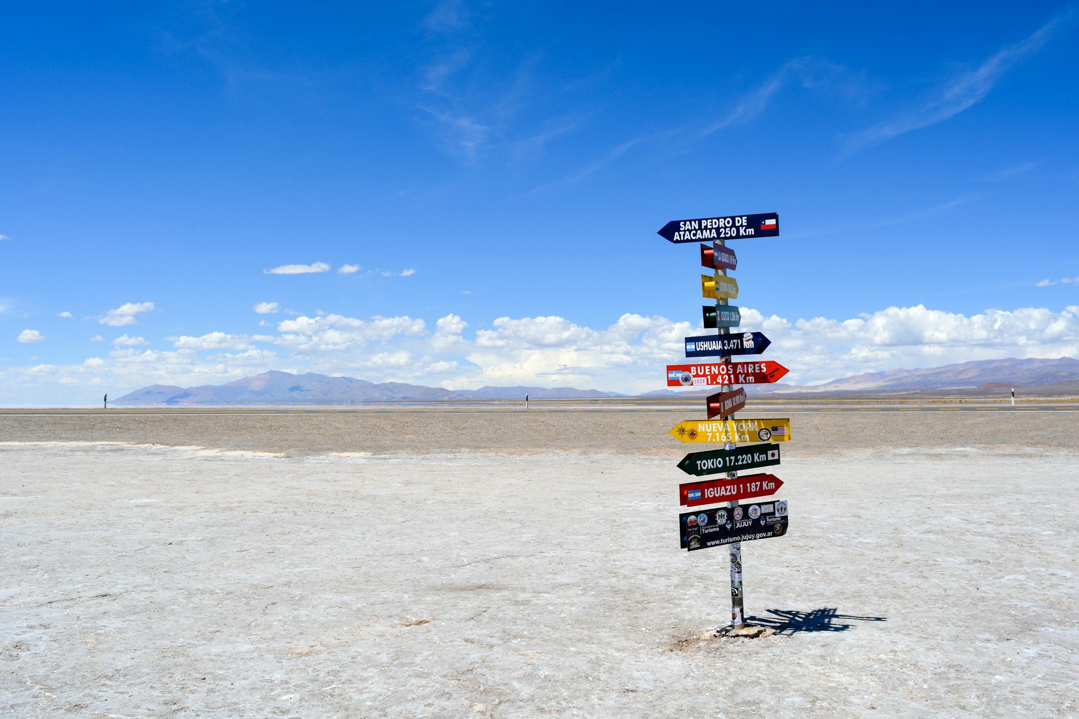 A bright signpost stands in a vast arid landscape with clear blue skies in Argentina.