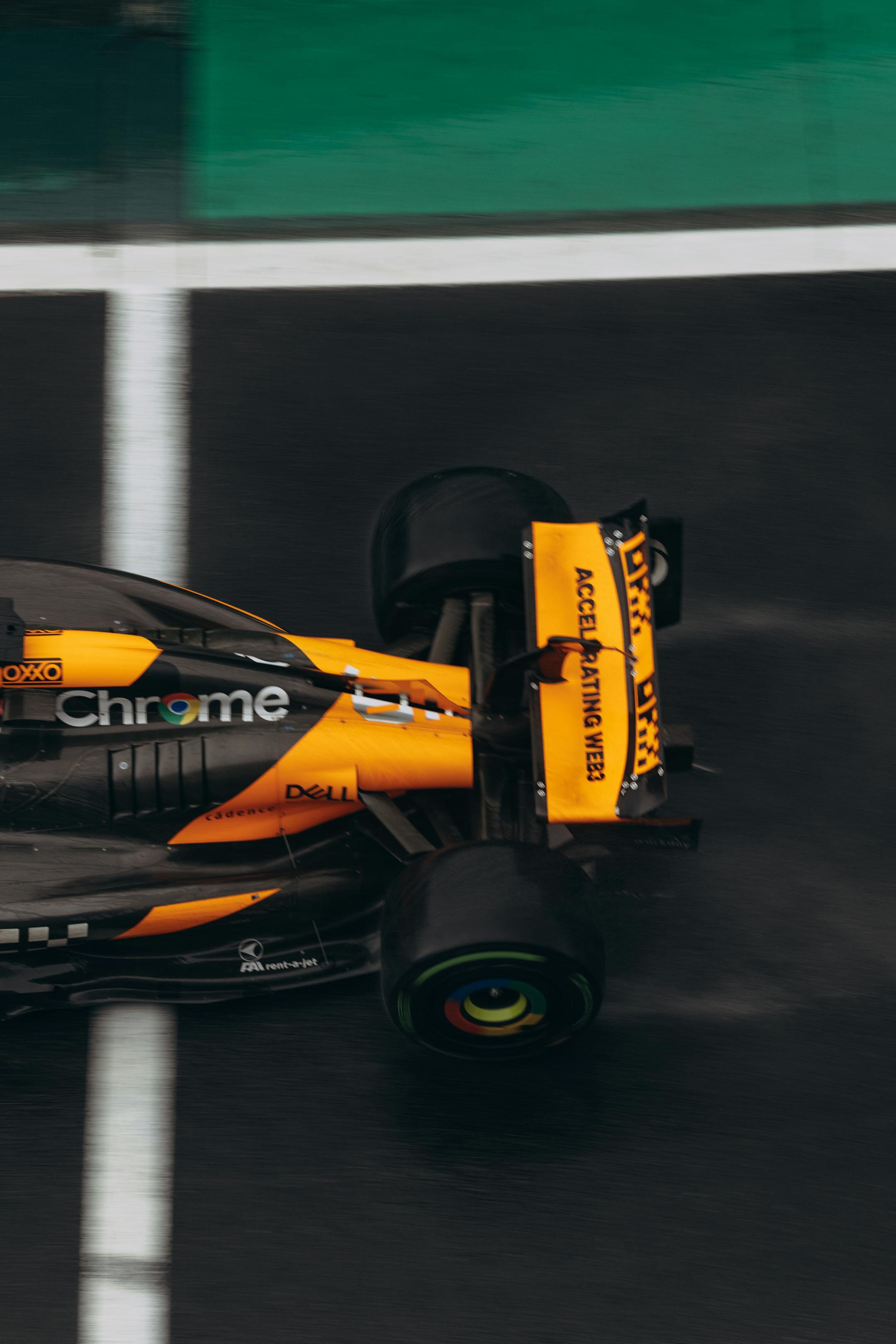 Top view of a fast-moving formula racing car on a wet track, showcasing speed and precision.