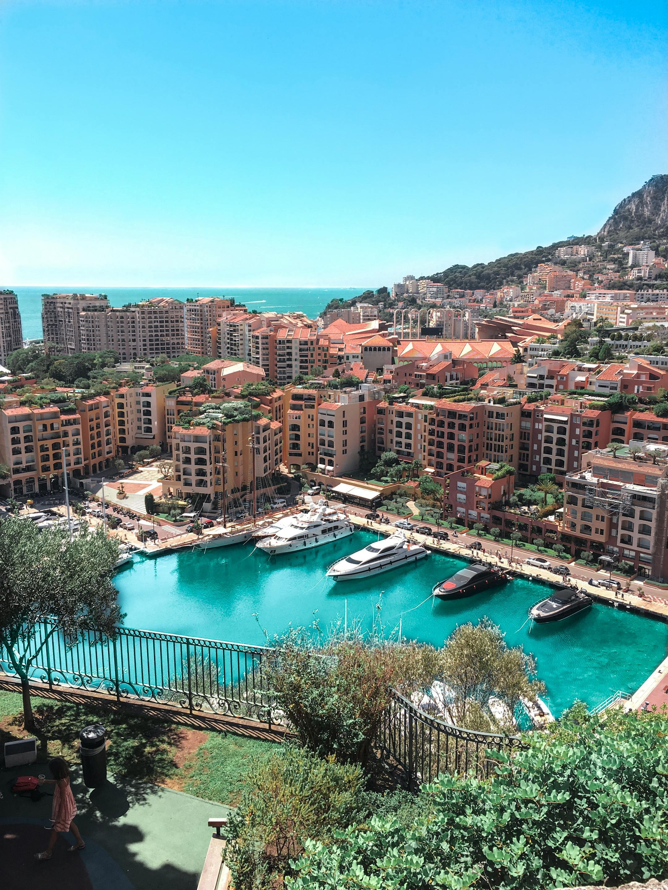 A stunning aerial view of Monte Carlo's vibrant harbor and surrounding cityscape under a clear blue sky.