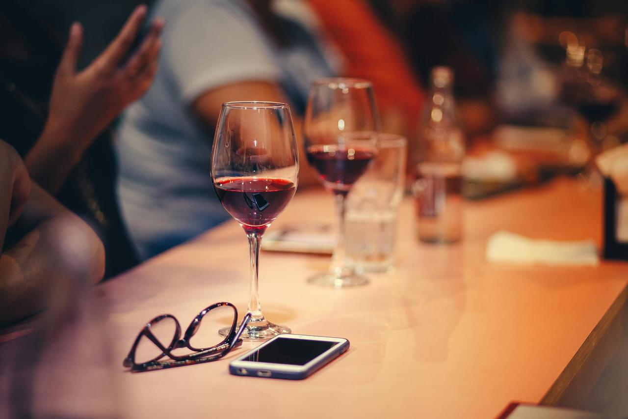 A cozy indoor gathering featuring wine glasses, a smartphone, and eyewear on a table.