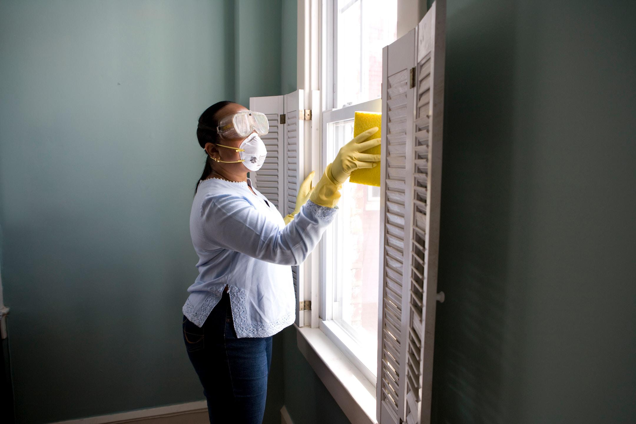 A woman cleaning windows in someone&#x27;s home.