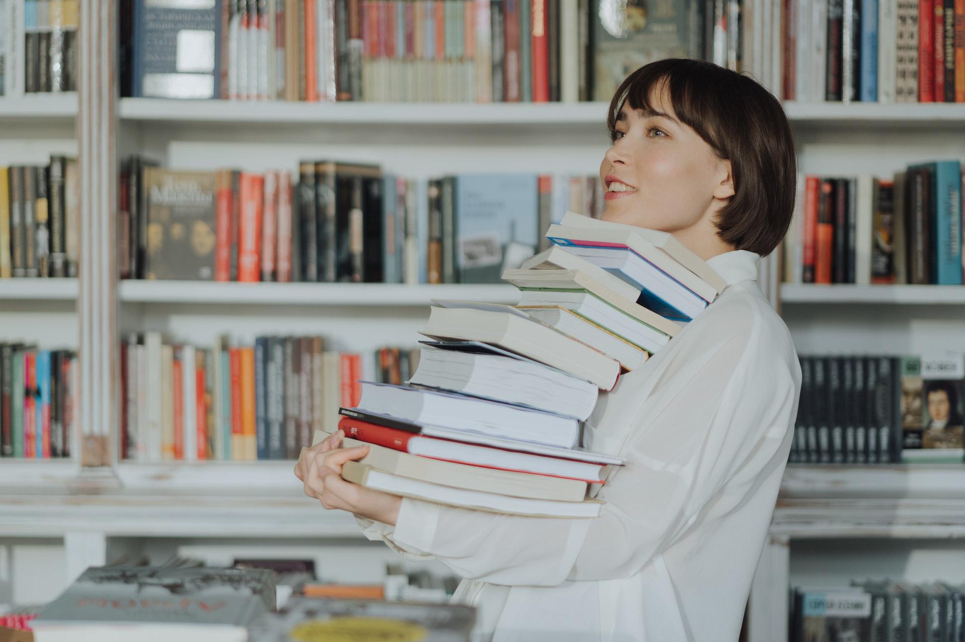 Woman holding a stack of books.